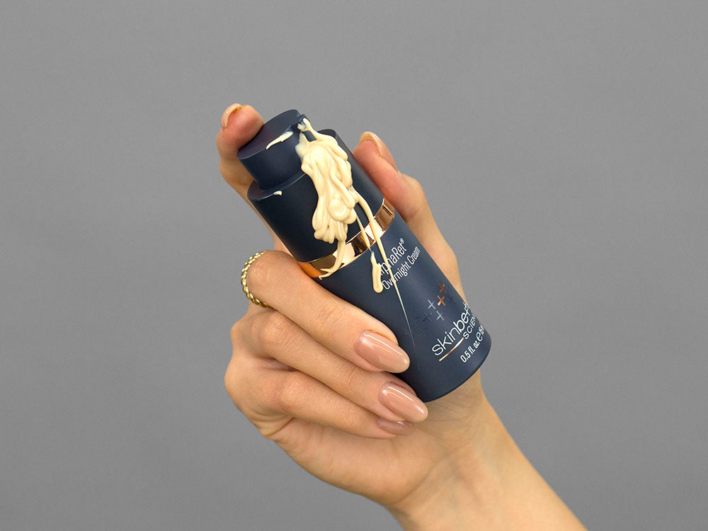 Closeup of Laziza from LAZ Skincare demonsatrating the pump on a bottle of Skinbetter Science AlphaRet Overnight