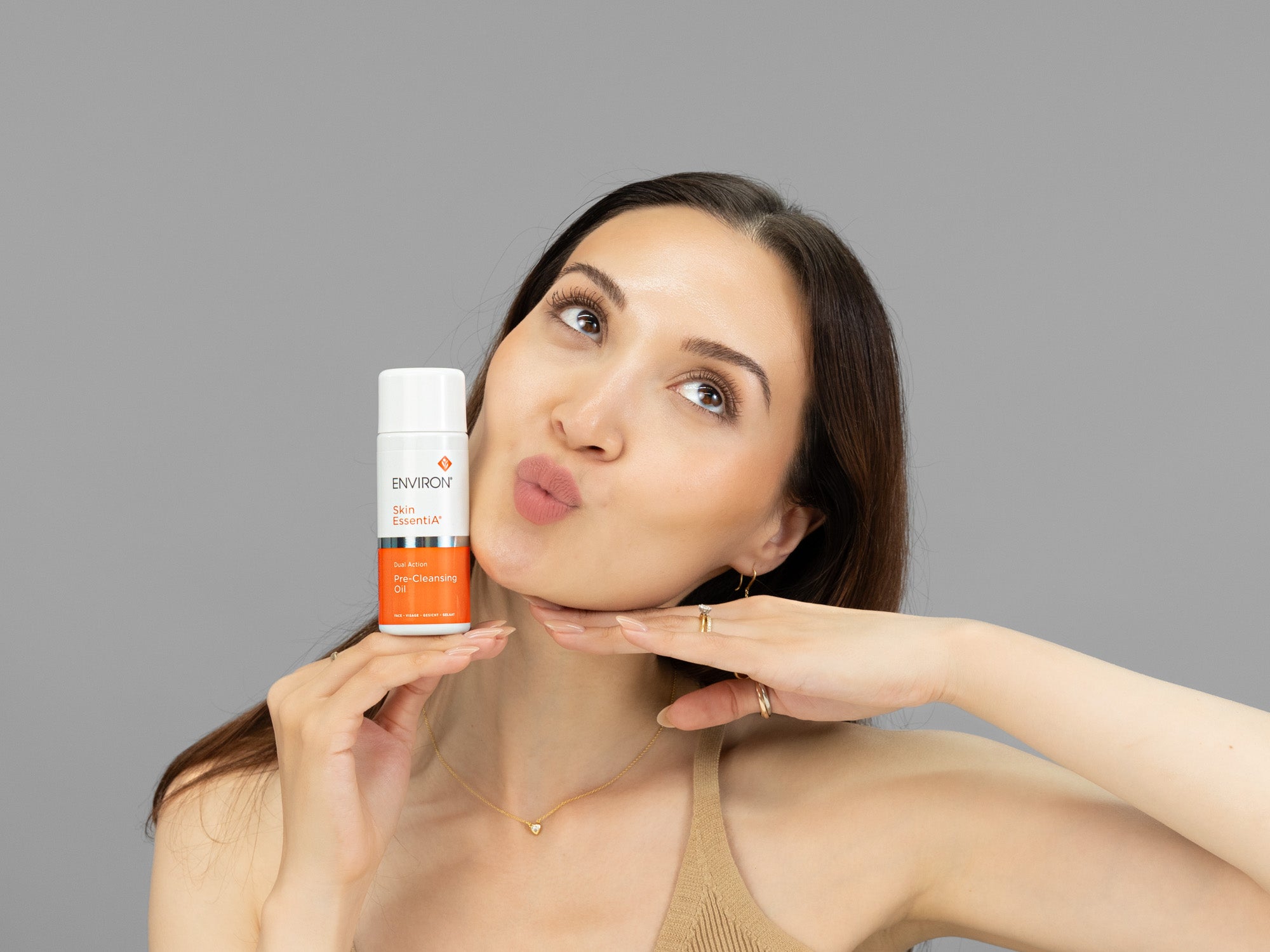 Laziza from LAZ Skincare holding a bottle of Environ Pre-Cleansing Oil up to her face