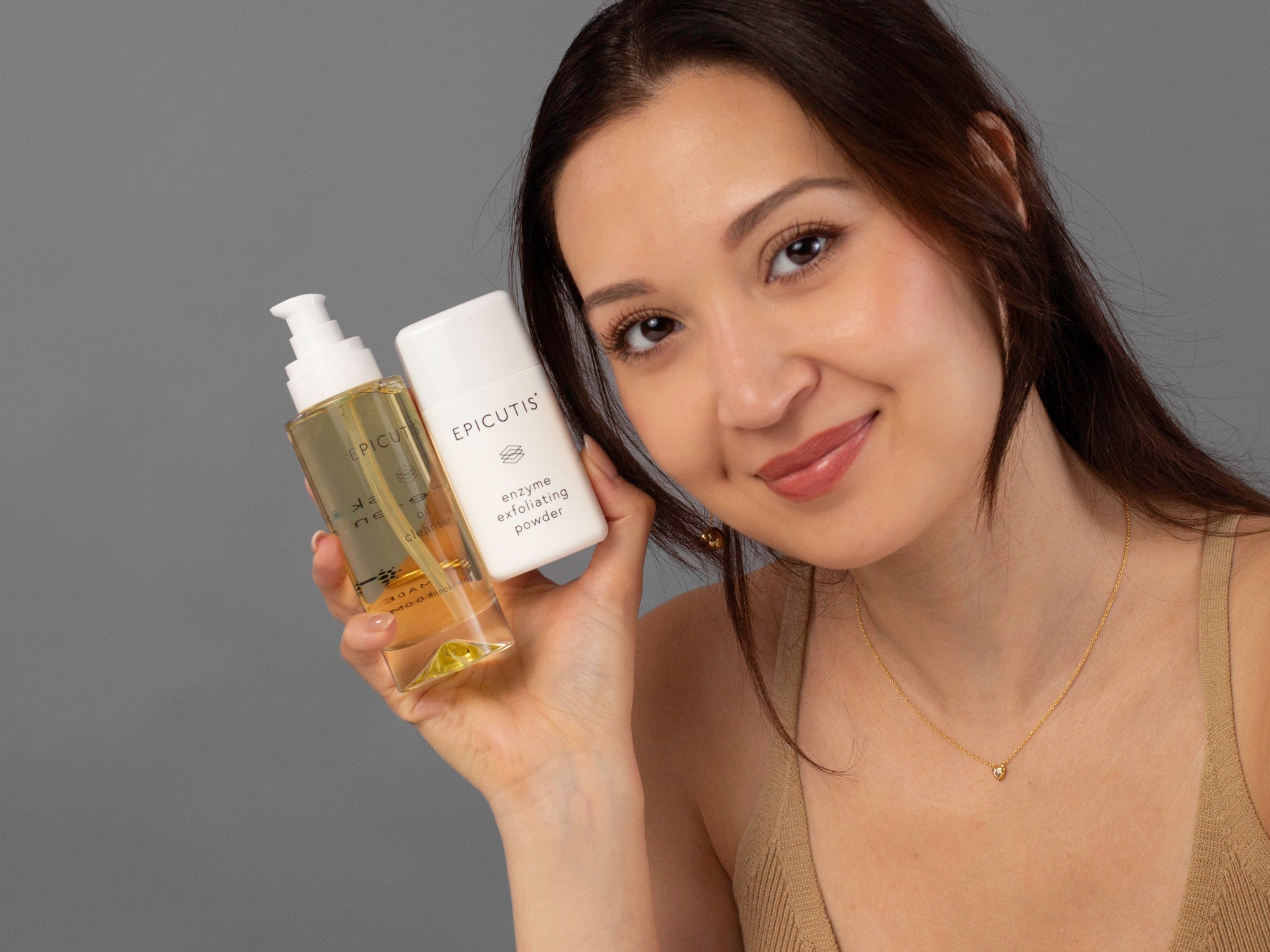 Laziza from LAZ Skincare holding the bottles of oil and enzyme exfoliating powder from the Epicutis Cleansing Essentials Set