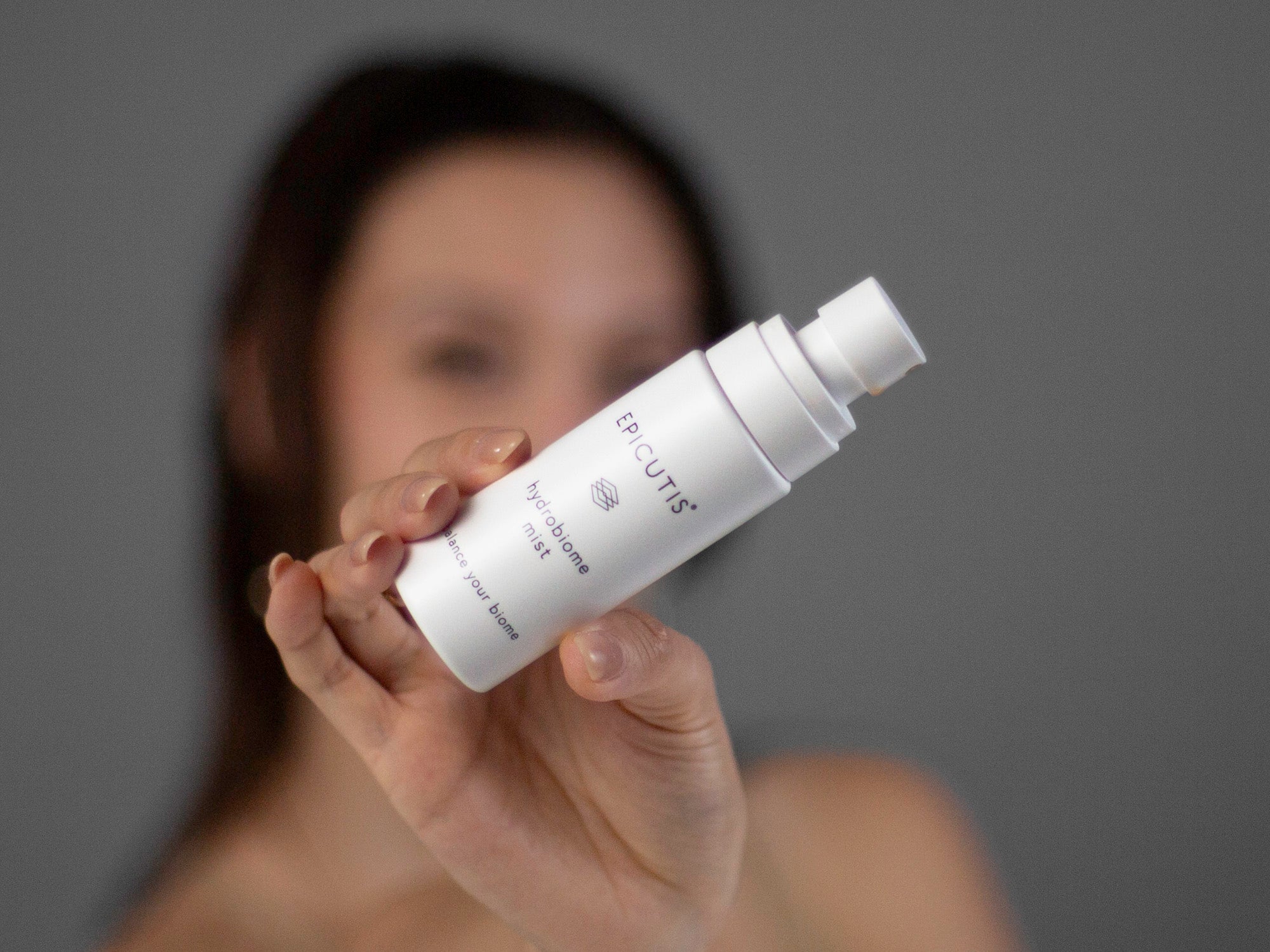 Closeup of Laziza from LAZ Skincare holding up a bottle of Epicutis Hydrobiome Mist with a blurred background