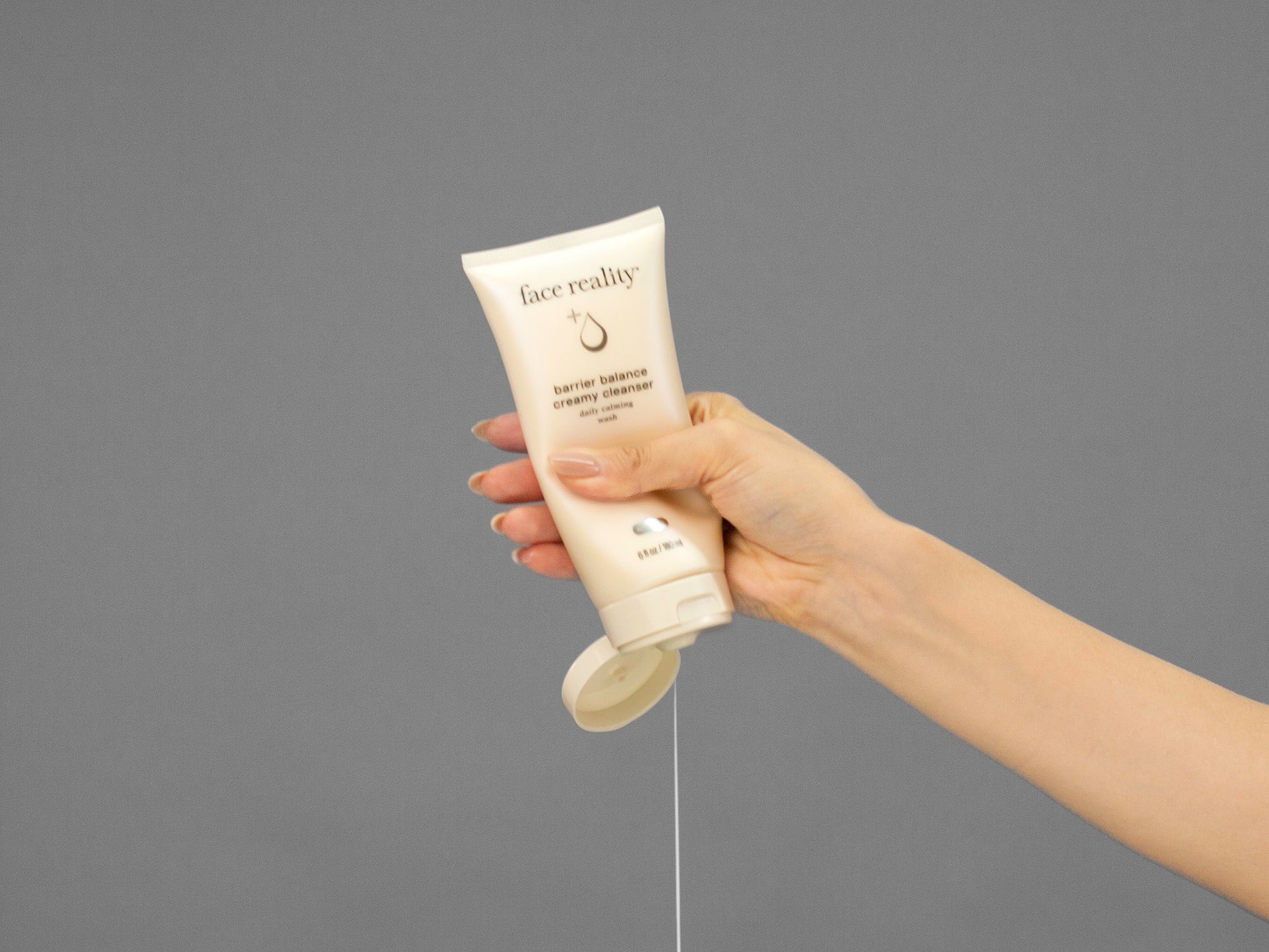 Closeup of Laziza from LAZ Skincare squeezing a tube of Face Reality Barrier Balance Creamy Cleanser