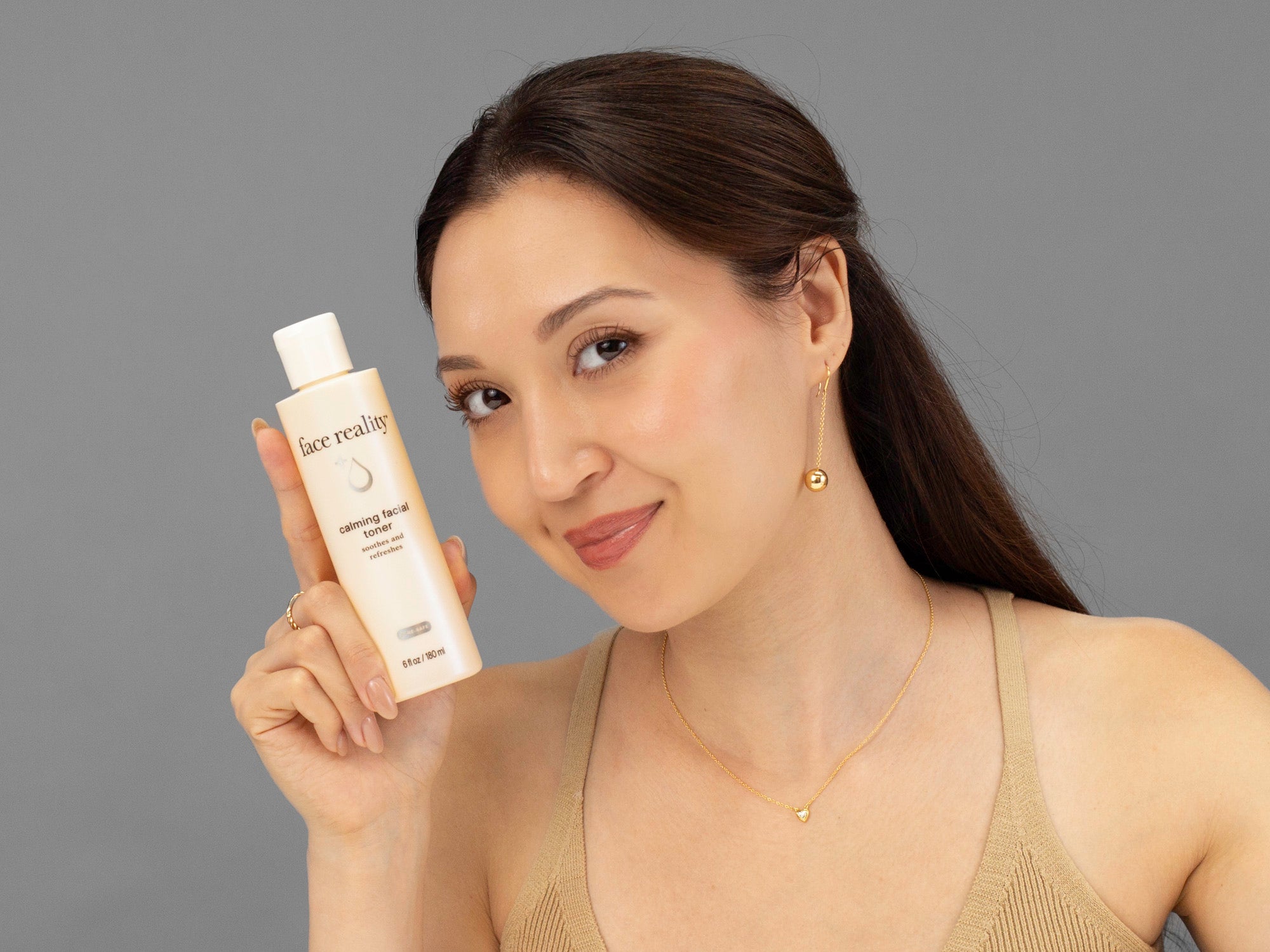 Laziza from LAZ Skincare holding a bottle of Face Reality Calming Facial Toner up to her face