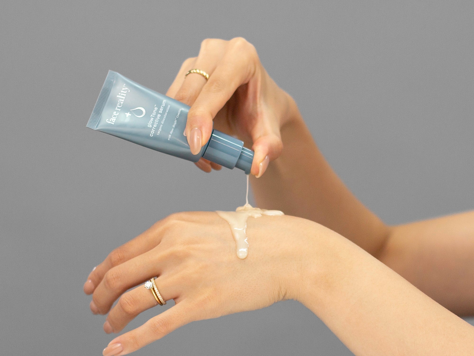 Laziza from LAZ Skincare pumping a tube of Face Reality GlowTone Corrective Serum out onto her hand