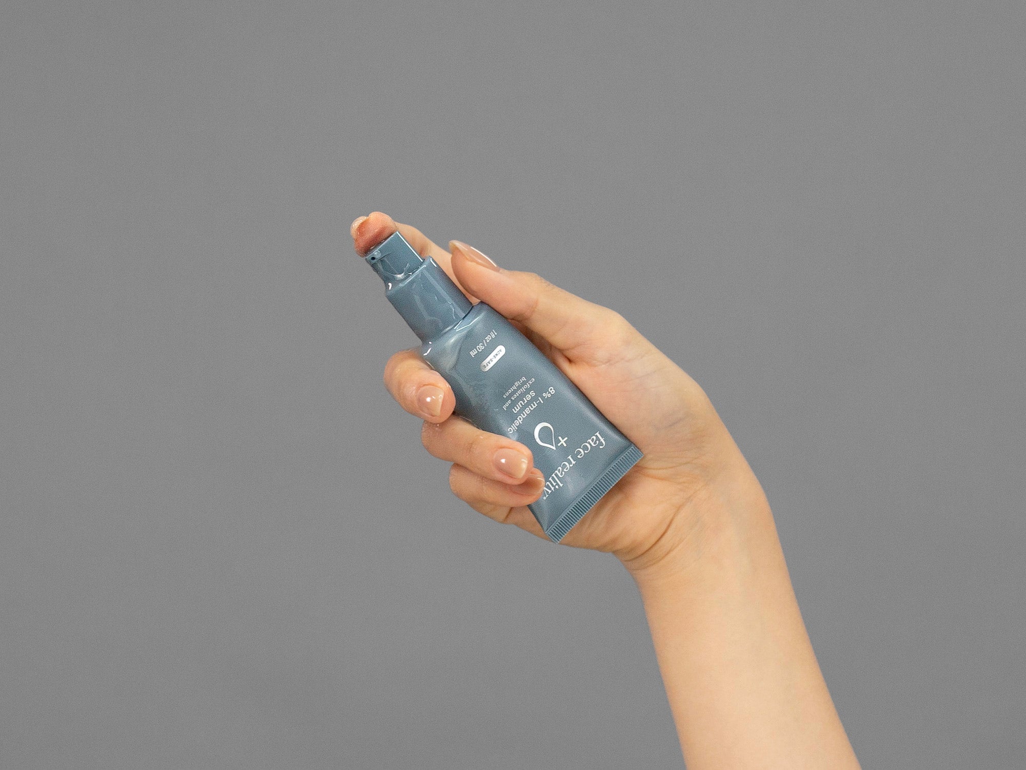 Closeup of Laziza from LAZ Skincare holding a tube of Face Reality Mandelic Serum in her hand