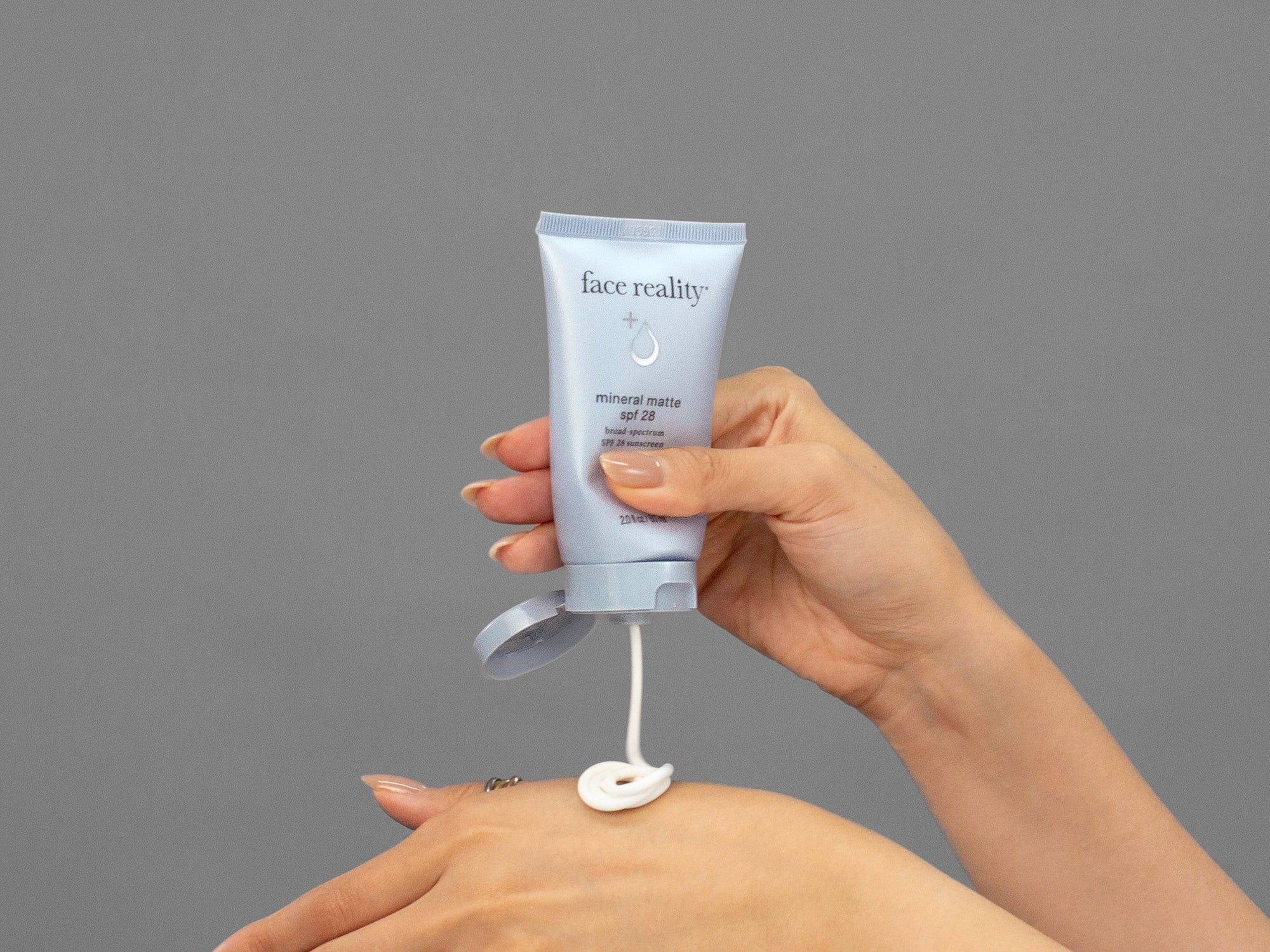 Closeup of Laziza from LAZ Skincare applying Face Reality Mineral Matte SPF28 sunscreen to her hand