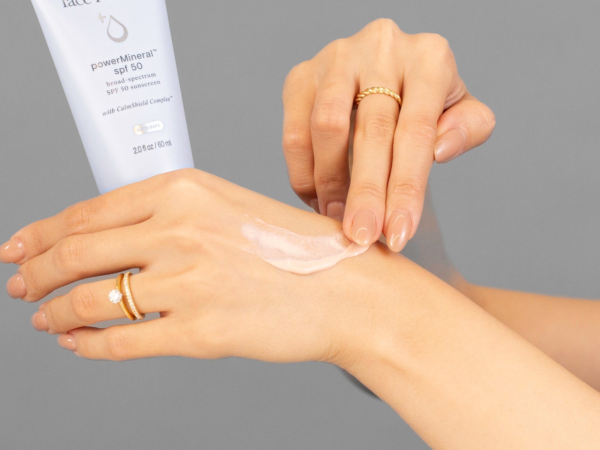 Closeup of Laziza from LAZ Skincare applying Face Reality Power Mineral SPF50 to her hand