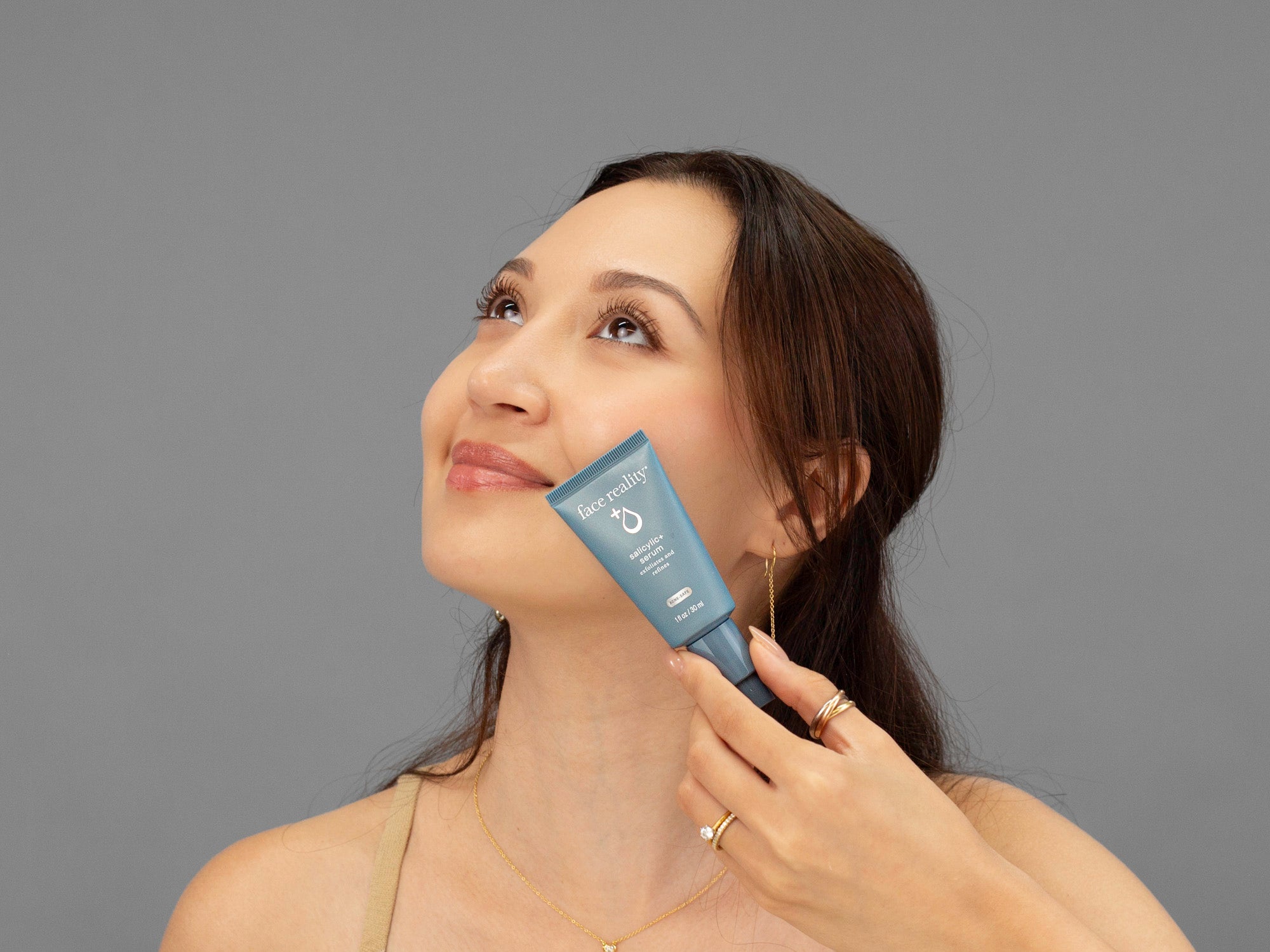 Laziza from LAZ Skincare holding a bottle of Face Reality Salicylic Serum up to her face