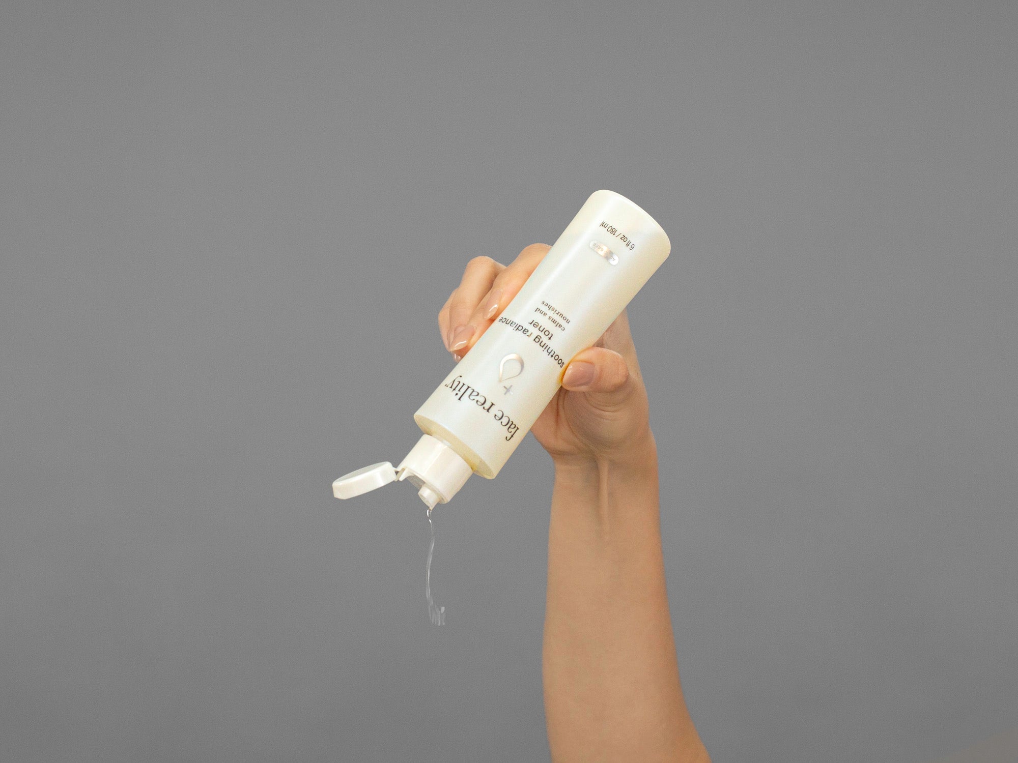 Closeup of Laziza from LAZ Skincare squeezing a bottle of Face Reality Soothing Radiance Toner