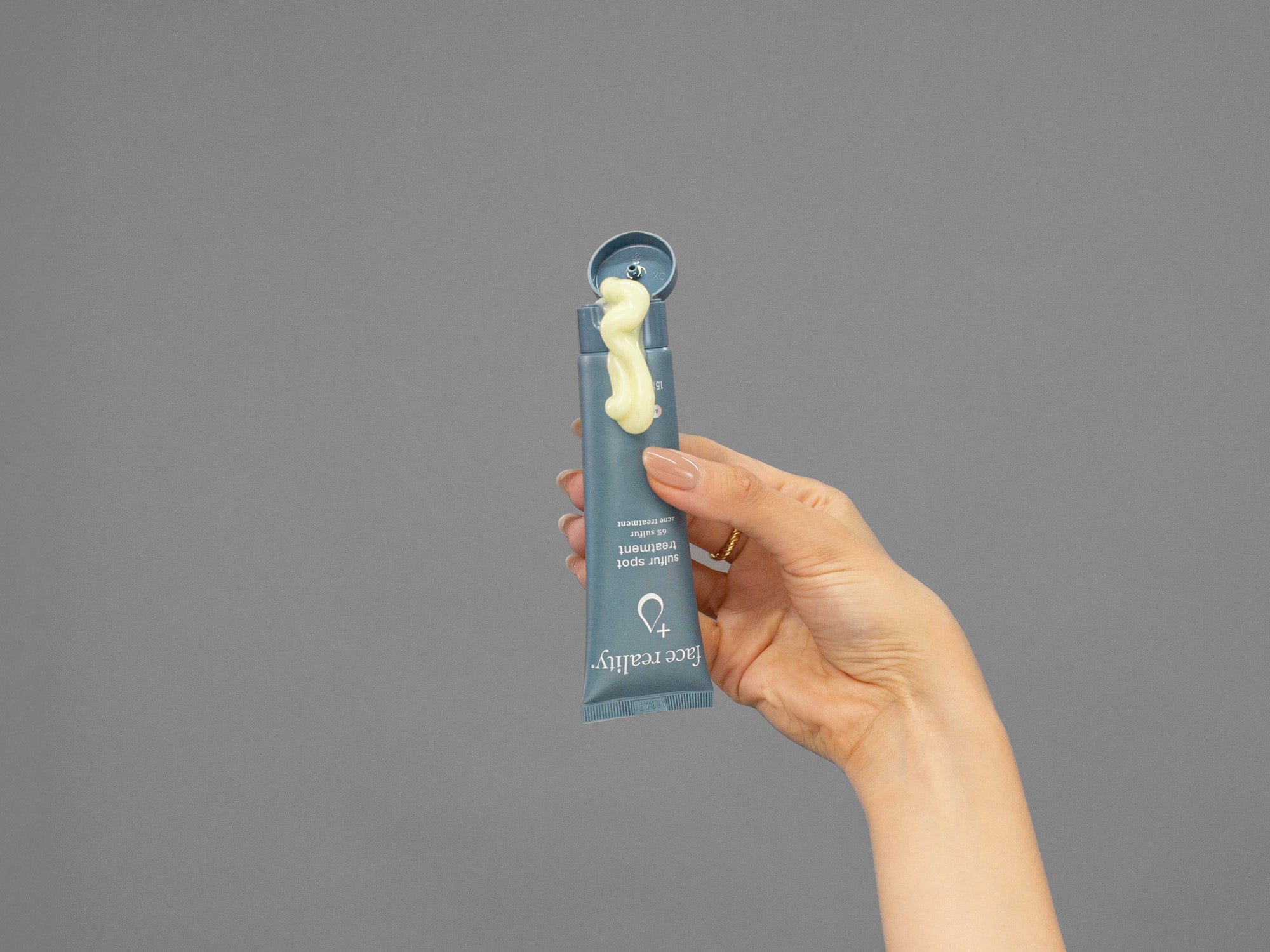 Closeup of Laziza from LAZ Skincare squeezing a tube of Face Reality Sulphur Spot Treatment in her hand