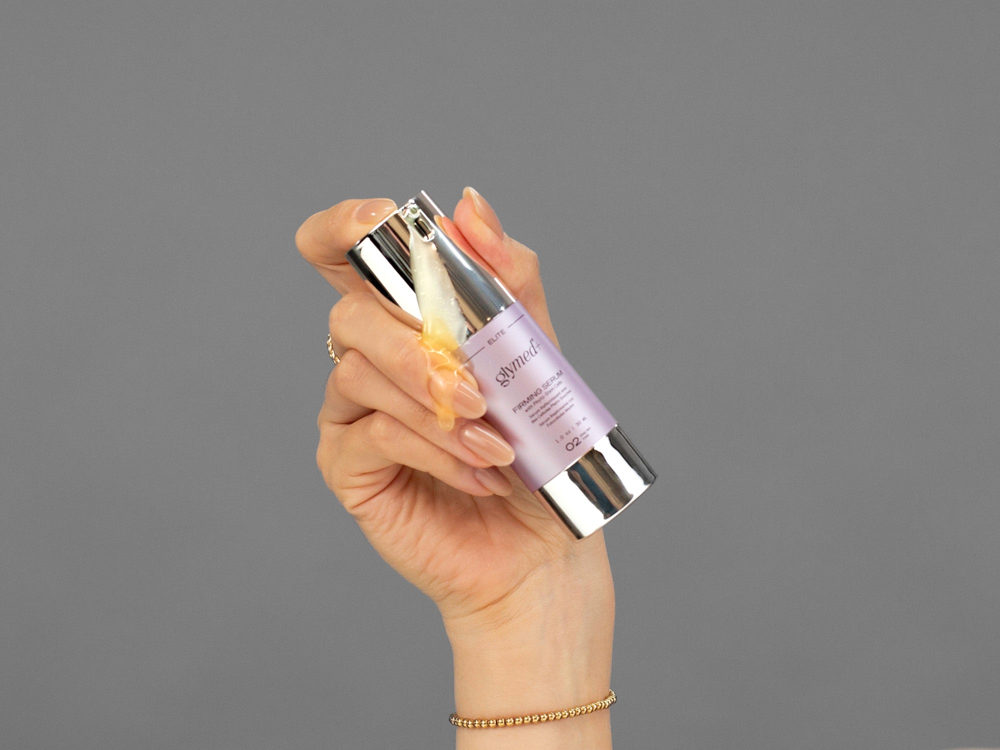 Closeup of Laziza from LAZ Skincare holding a bottle of GlyMed Firming Serum in her hand