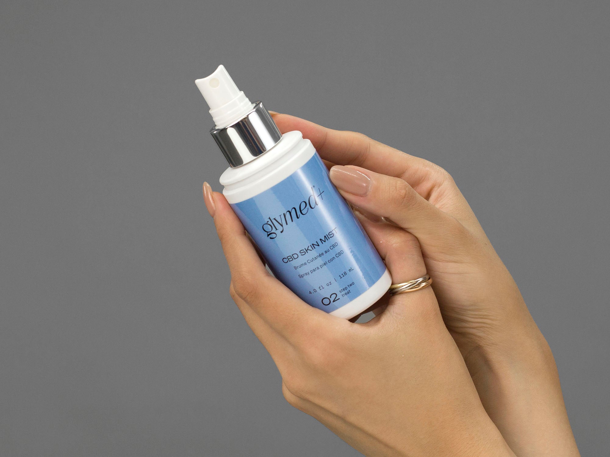 Closeup of Laziza from LAZ Skincare holding bottle of GlyMed Help Ski Mist in her hands