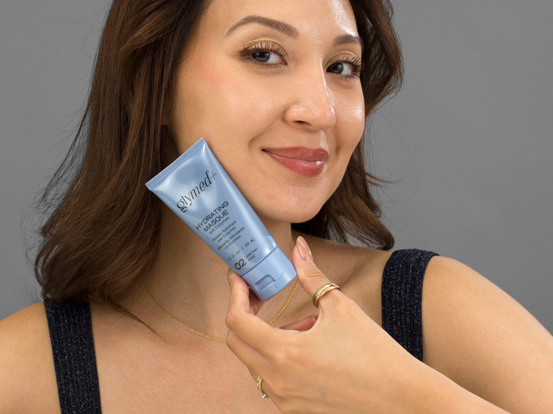 Laziza from LAZ Skincare holding a bottle of GlyMed Hydrating Masque up to her face