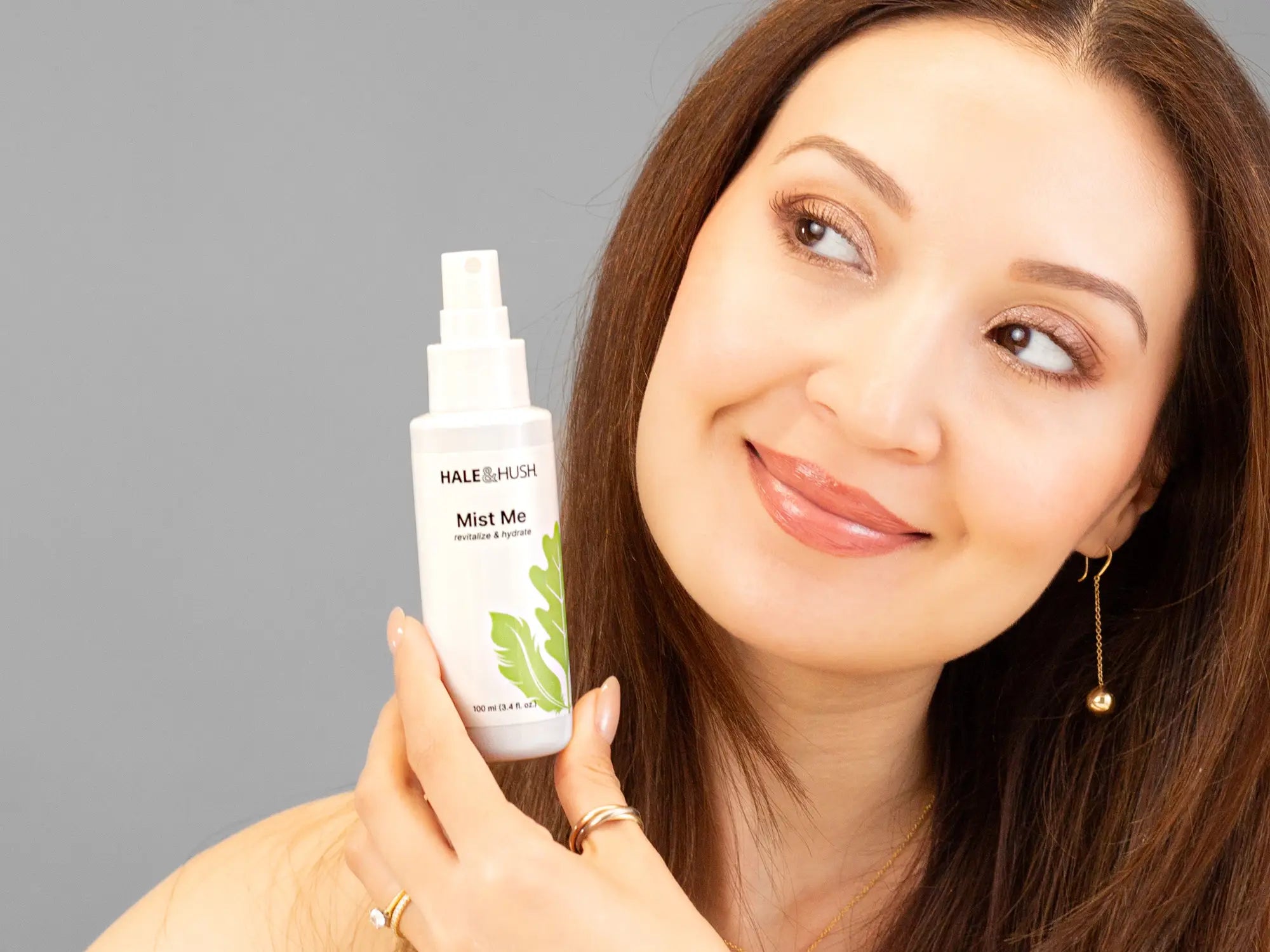 Laziza from LAZ Skincare holding a bottle of Hale & Hush Mist Me up to her face
