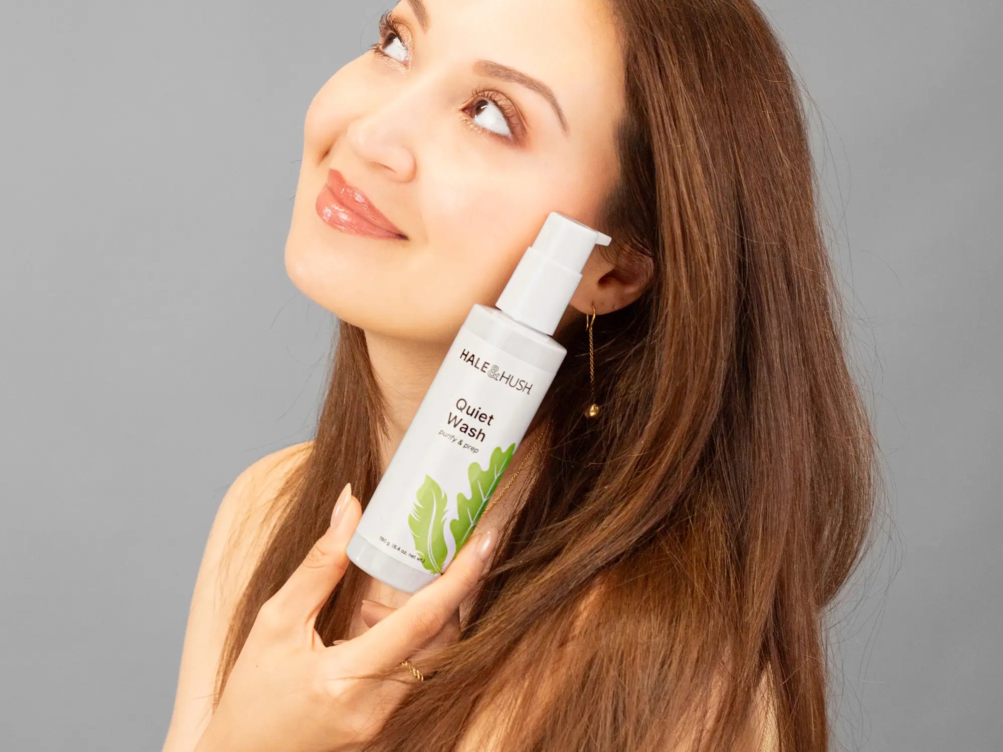 Laziza from LAZ Skincare holding a bottle of Hale & Hush Quiet Wash up to her face