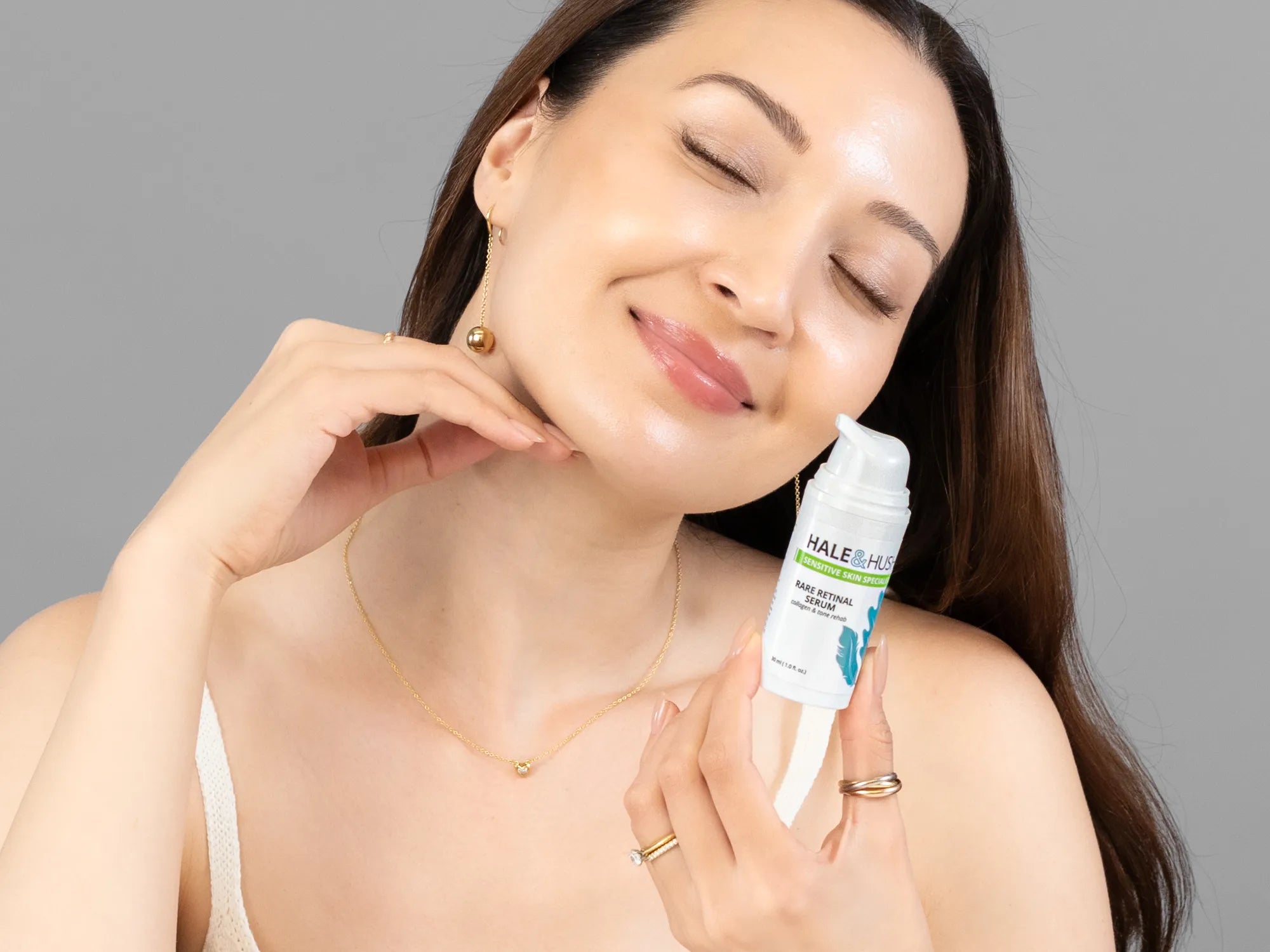 Laziza from LAZ Skincare holding a bottle of Hale & Hush Rare Retinal Serum up to her face