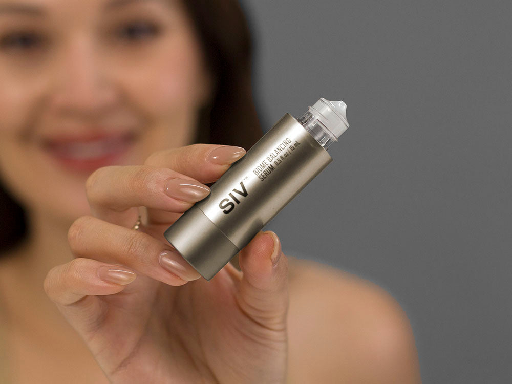 Closeup of Laziza from LAZ Skincare holding a bottle of SIV Biome Balancing Serum with a blurred background