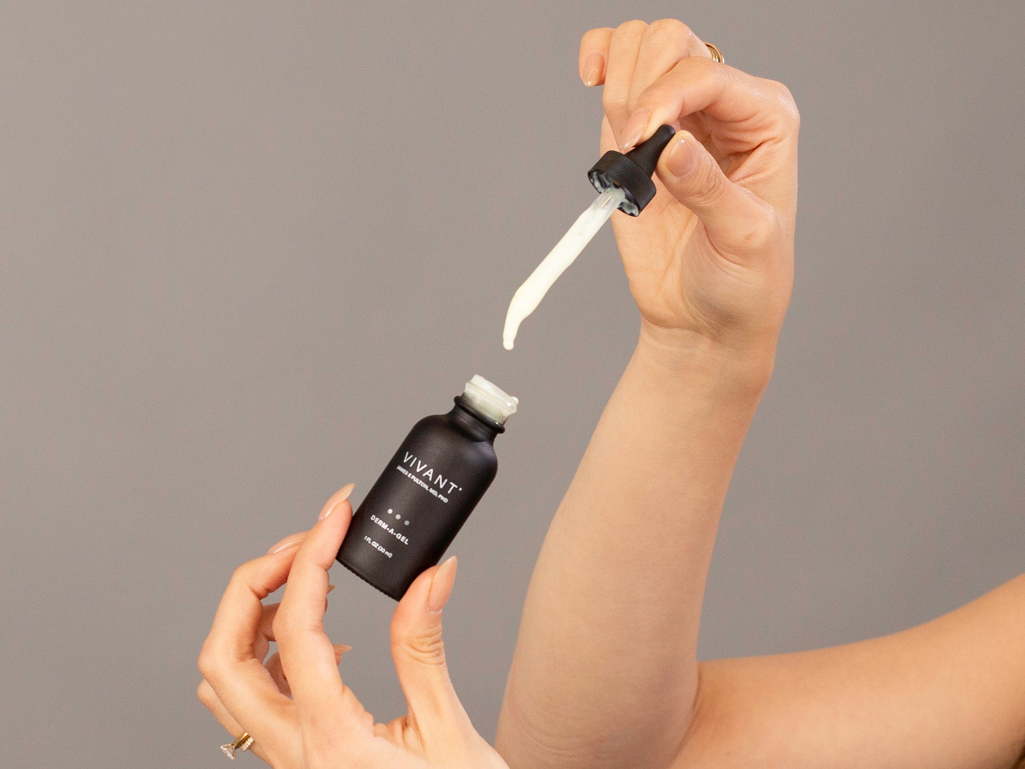 Closeup of Laziza from LAZ Skincare holding a dropper and bottle of Vivant Derm-A-Gel