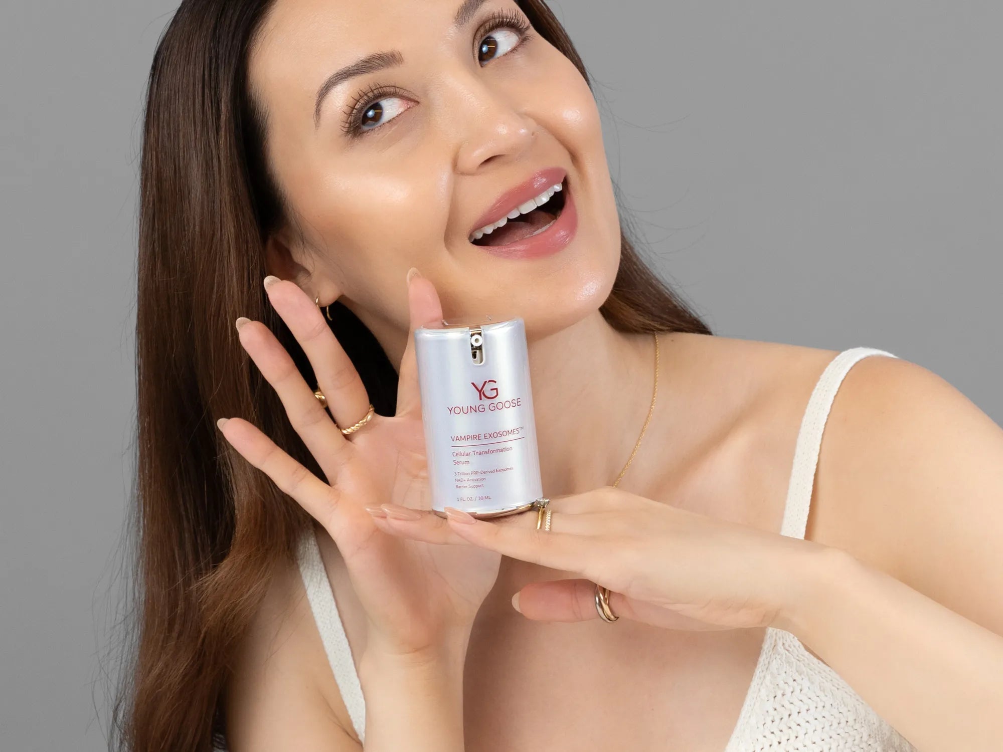 Laziza from LAZ Skincare holding a bottle of Young Goose Vampire Exosomes up to her face