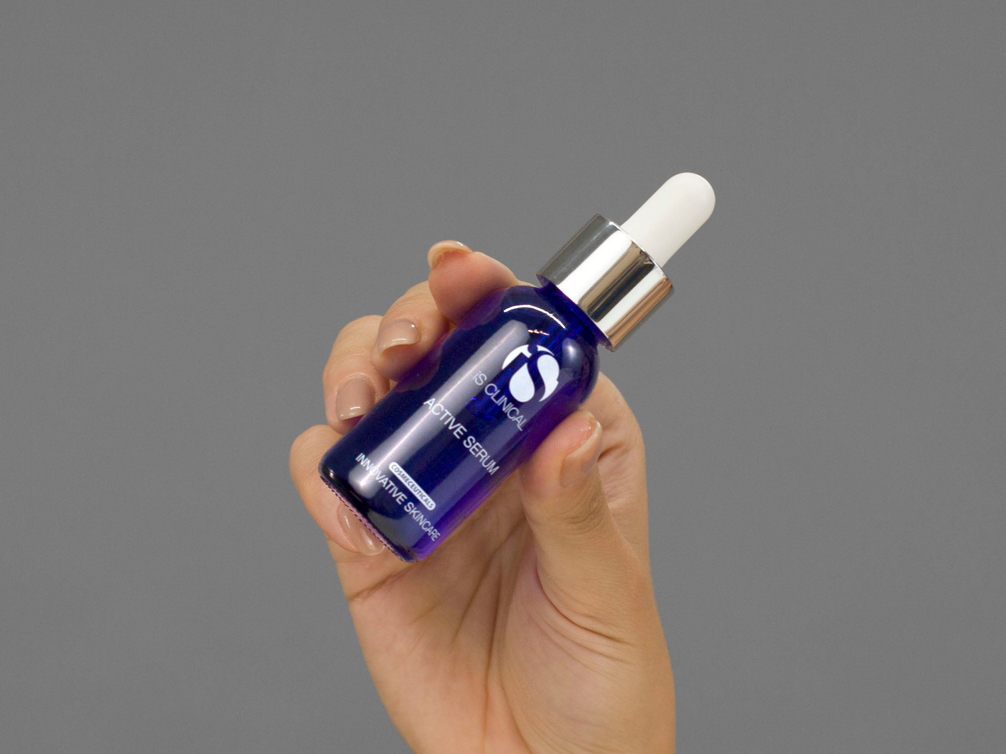 Closeup of Laziza from LAZ Skincare holding a bottle of iS Clinical Active Serum in her hand