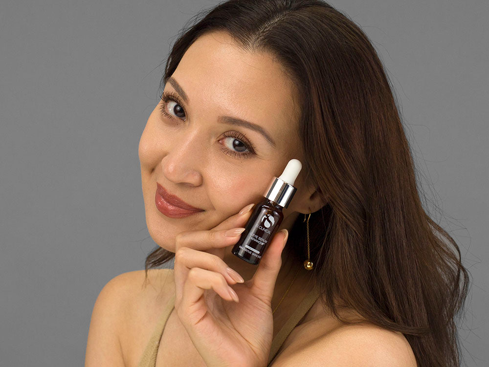Laziza from LAZ Skincare holding a bottle of iS Clinical C Eye Serum Advance up to her face