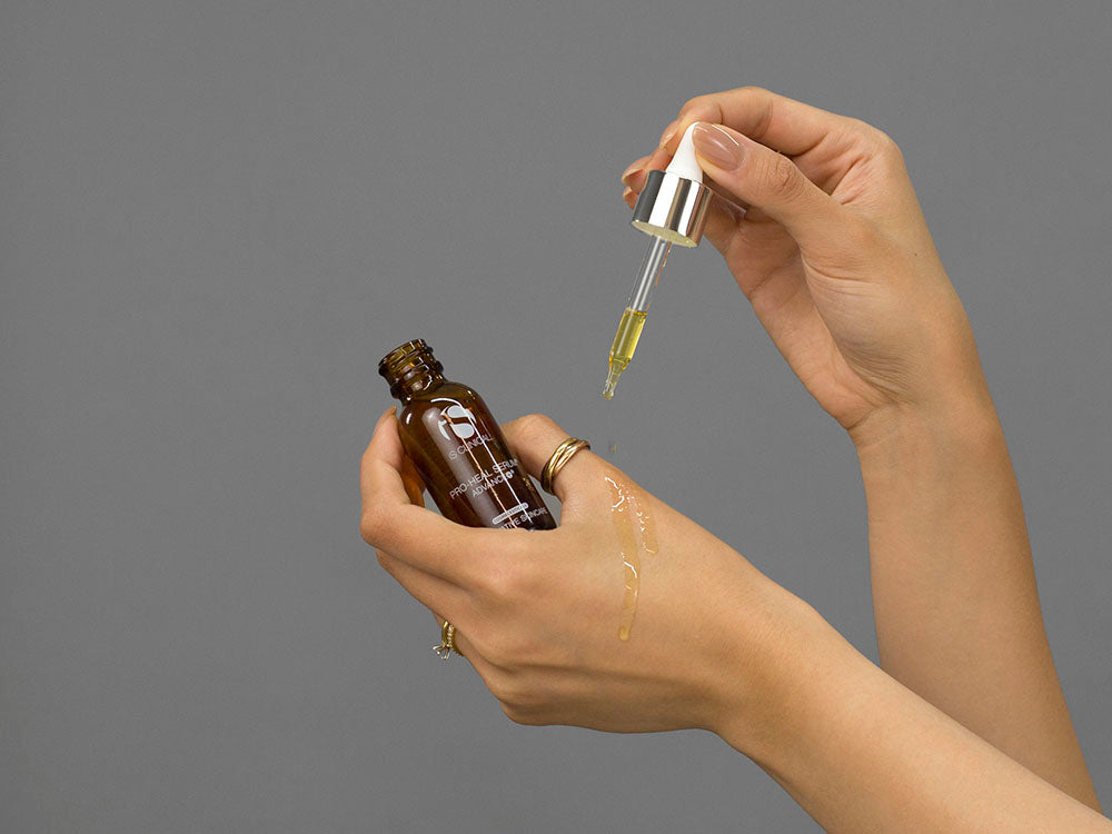 Closeup of Laziza from LAZ Skincare demonstrating the dropper and bottle of iS Clinical Pro-Heal Serum Advance