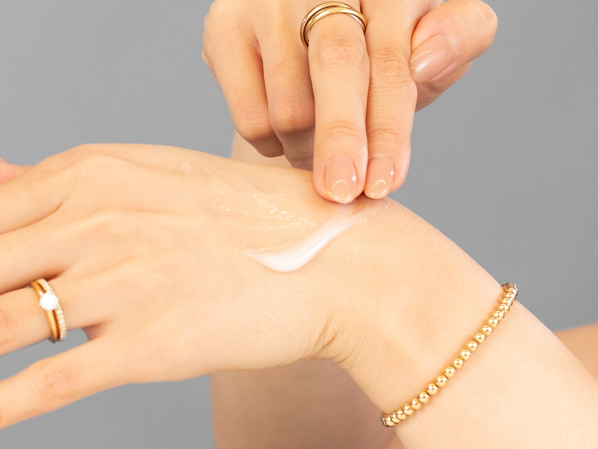 Laziza from LAZ Skincare applying Alastin HA Immerse Serum to her hand on a neutral background