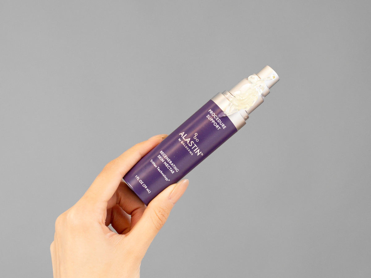Closeup of Laziza from LAZ Skincare holding up a bottle of Alastin Regenerating Skin Nectar