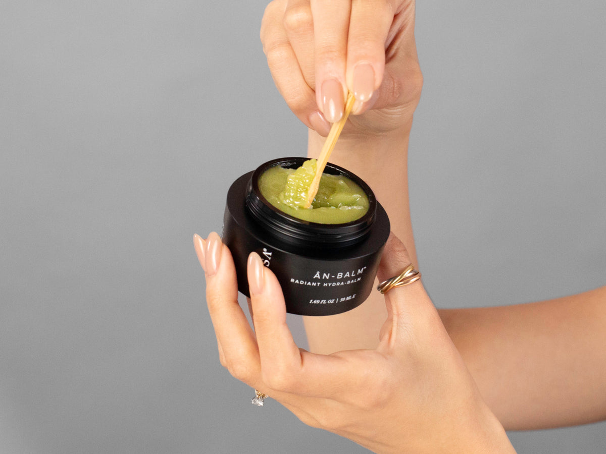 Closeup of Laziza from LAZ Skincare holding up a bottle of Anfisa ÂN-BALM