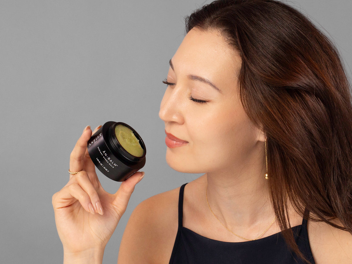 Laziza from LAZ Skincare holding a bottle of Anfisa ÂN-BALM up to her face