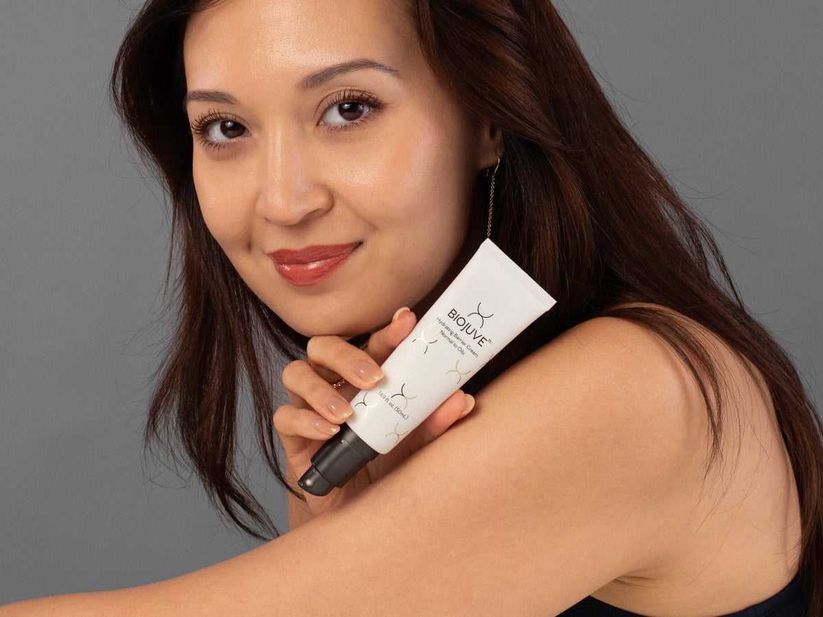 Laziza from LAZ Skincare holding a bottle of Biojuve Hydrating Barrier Cream up to her face