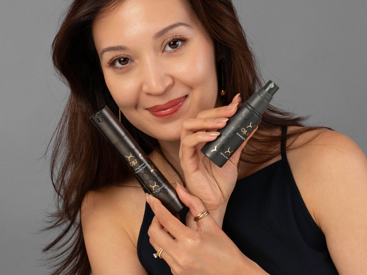 Laziza from LAZ Skincare holding a bottle of Biojuve Living Biome Essentials Serum Duo up to her face