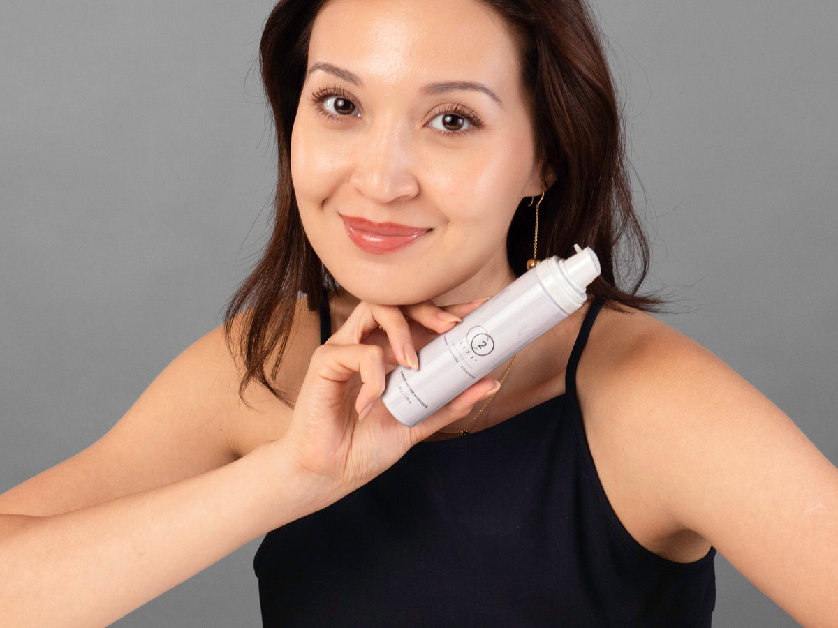 Laziza from LAZ Skincare holding a bottle of Lumisque CO2Lift Carboxy Mousse Moisturizer up to her face