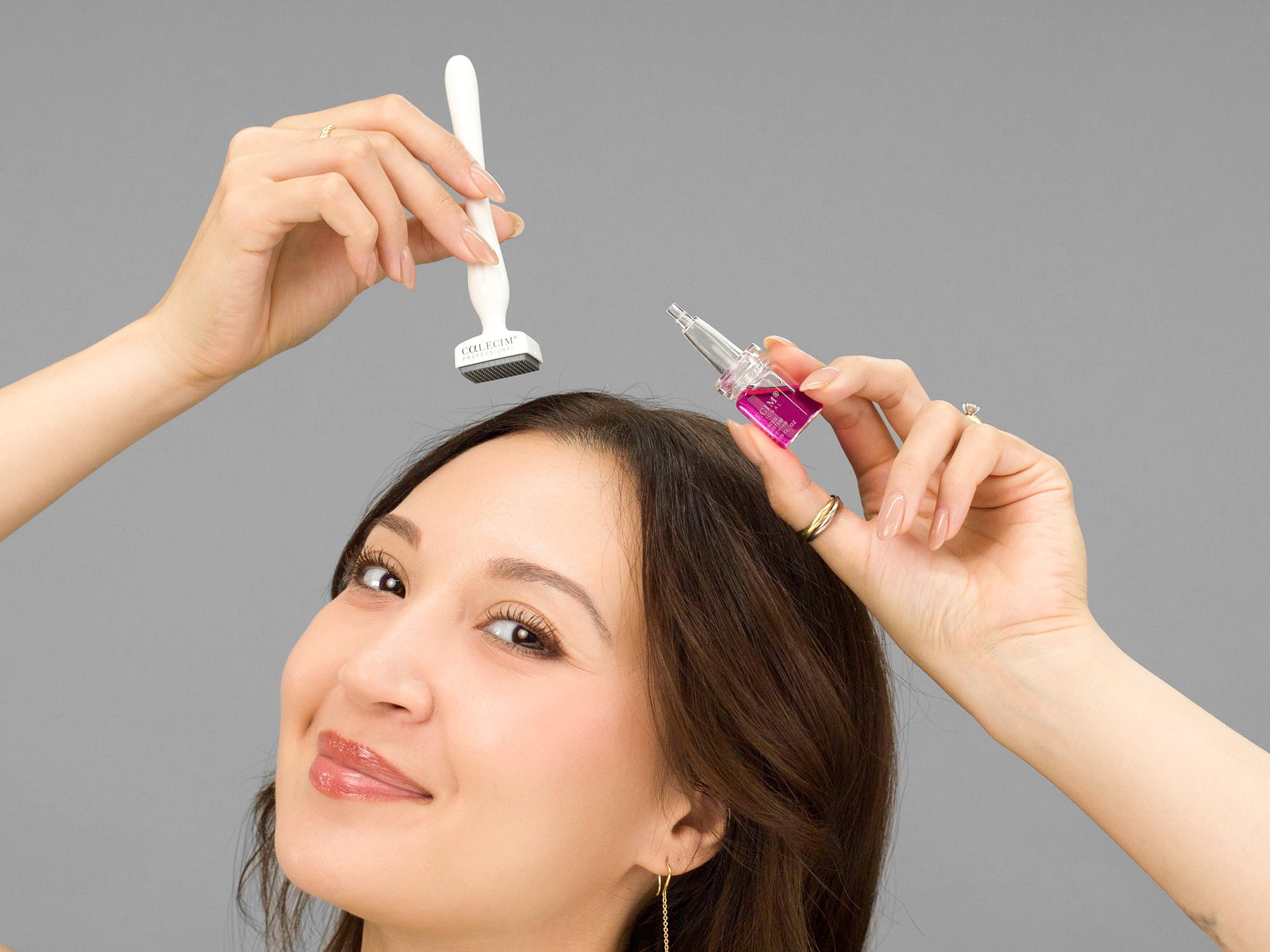 Laziza from LAZ Skincare holding the solution bottle and dermastamp Calecim Advanced Hair System above her head