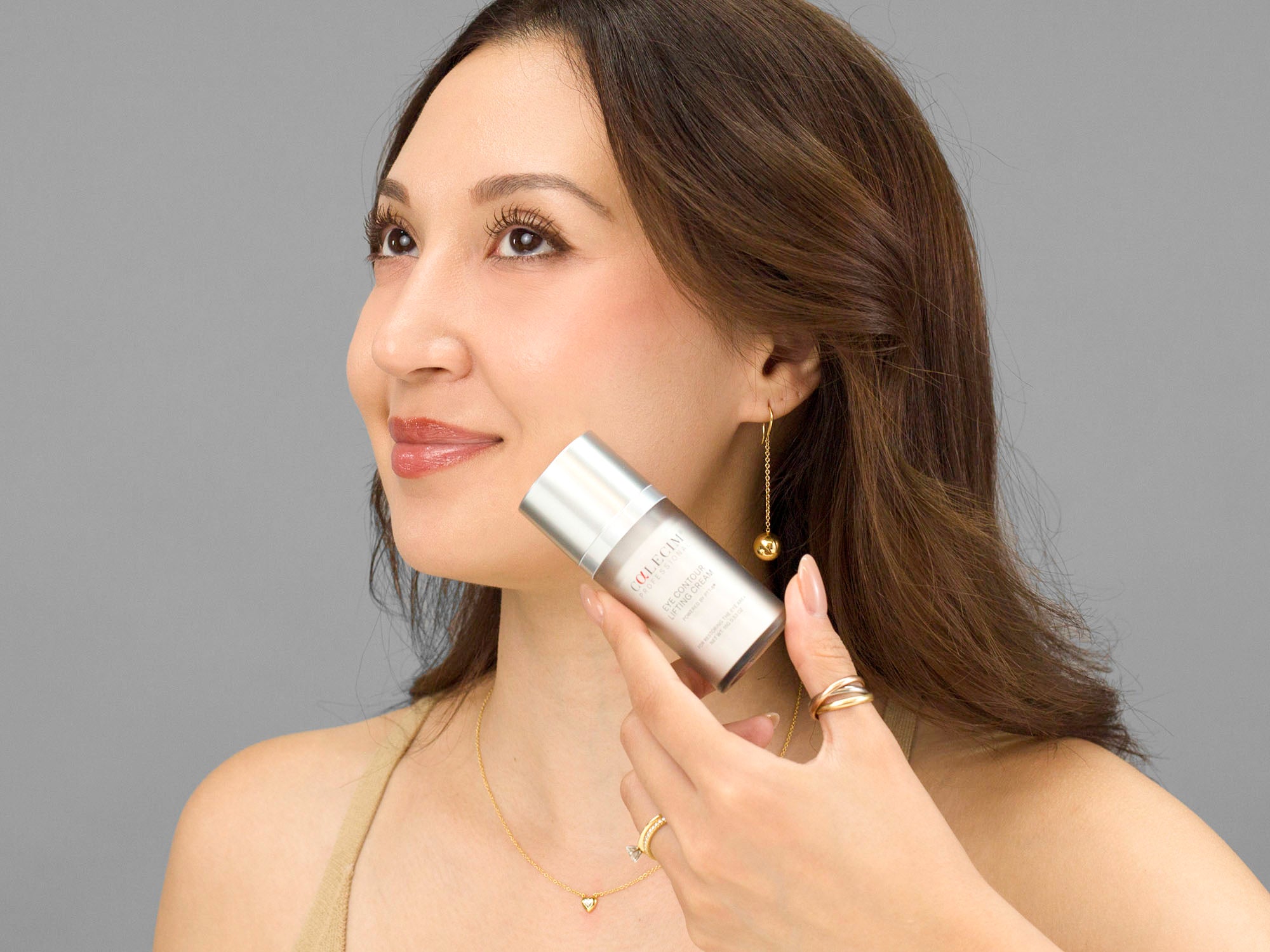 Laziza from LAZ Skincare holding a bottle of Calcium Eye Contour Lifting Cream up to her face