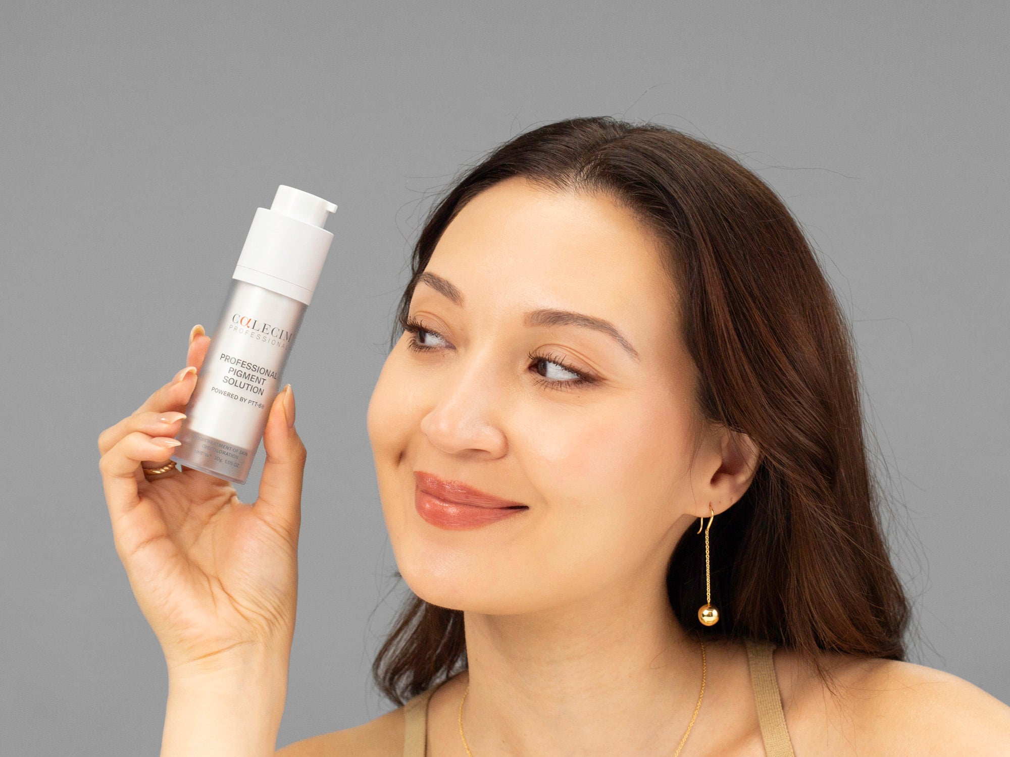 Laziza from LAZ Skincare holding up a bottle of Calecim Professional Pigment Solution next to her face