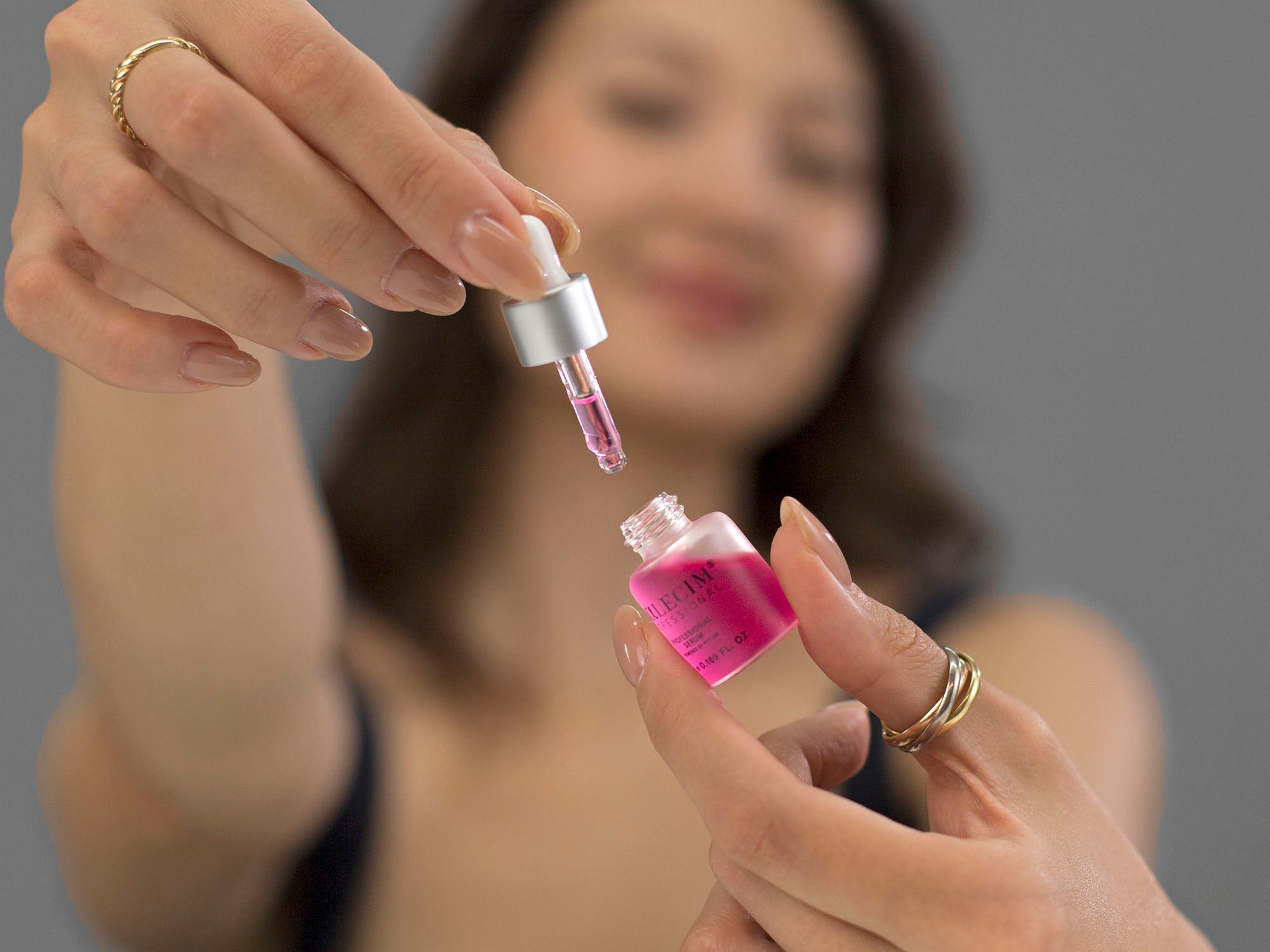 Laziza from LAZ Skincare holding up the dropper and bottle from Calecim Professional Serum with a blurred background