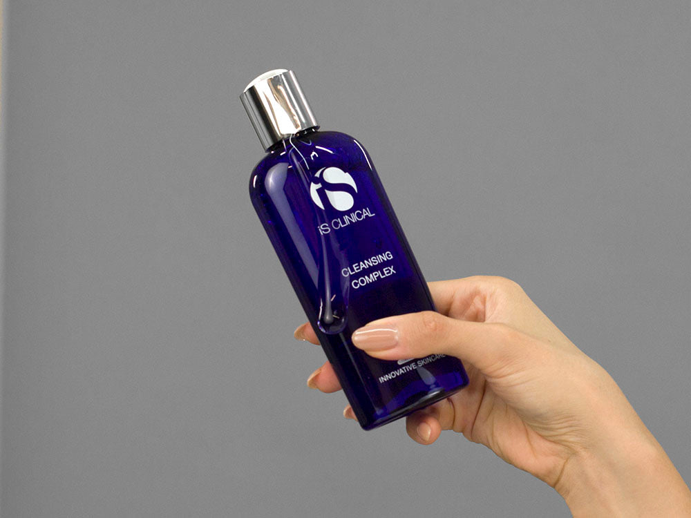 Closeup of Laziza from LAZ Skincare holding up a bottle of iS Clinical Cleansing Complex
