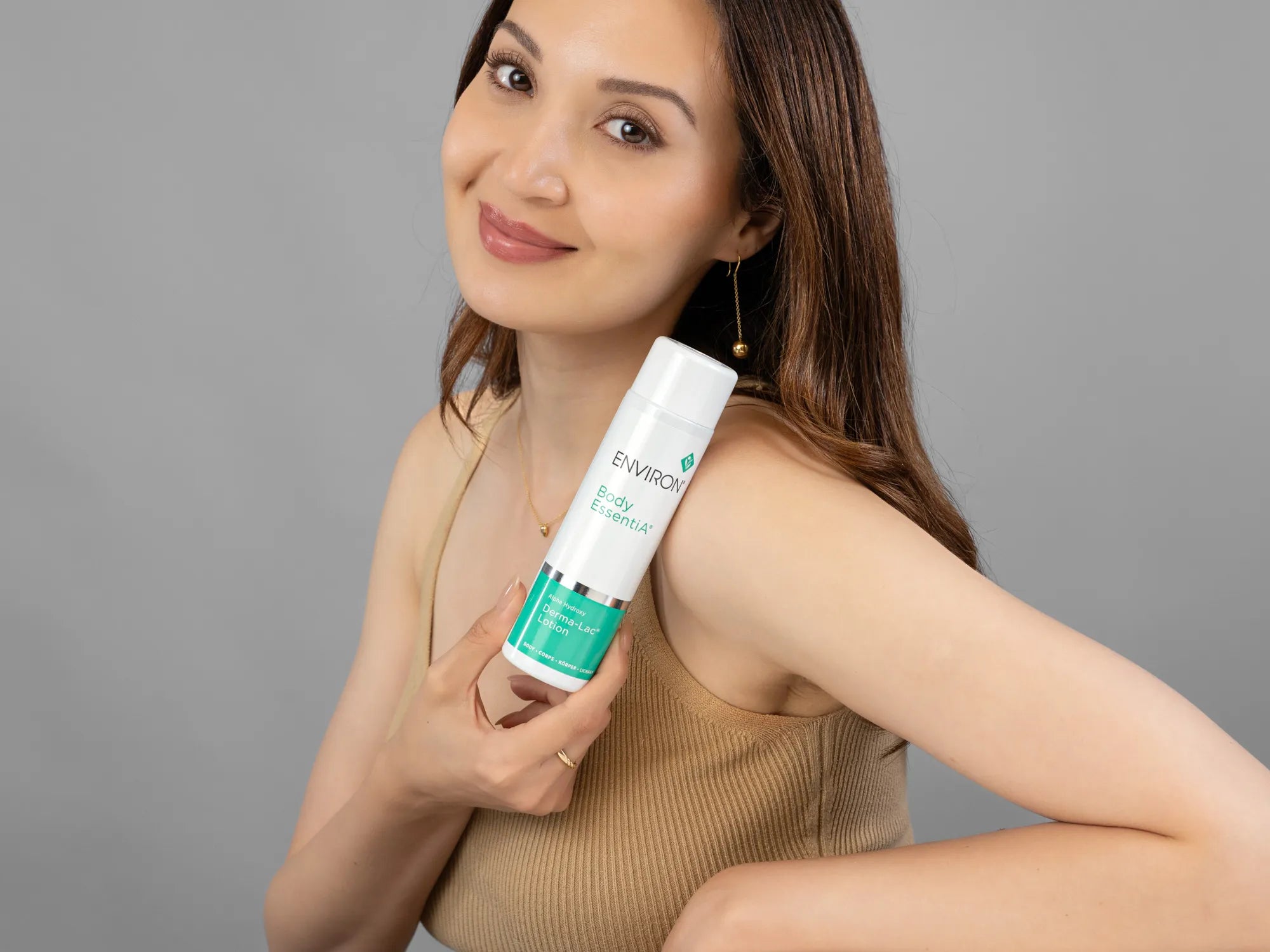 Laziza from LAZ Skincare holding a bottle of Environ Derma-Lac Lotion up to her face