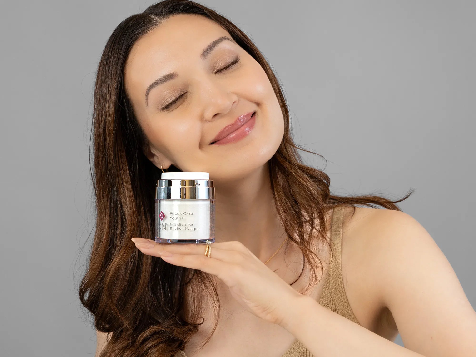 Laziza from LAZ Skincare holding a bottle of Environ Tri Bio-Botanical Revival Masque up to her face