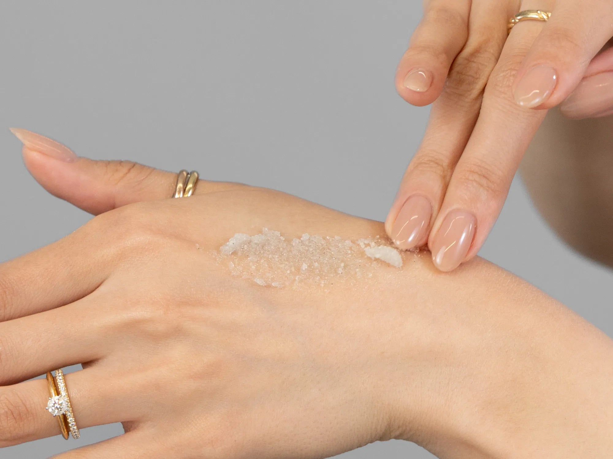 Laziza from LAZ Skincare demonstrating the texture and application of Epicuren Mint Renewal White Sand Body Polish on her hand