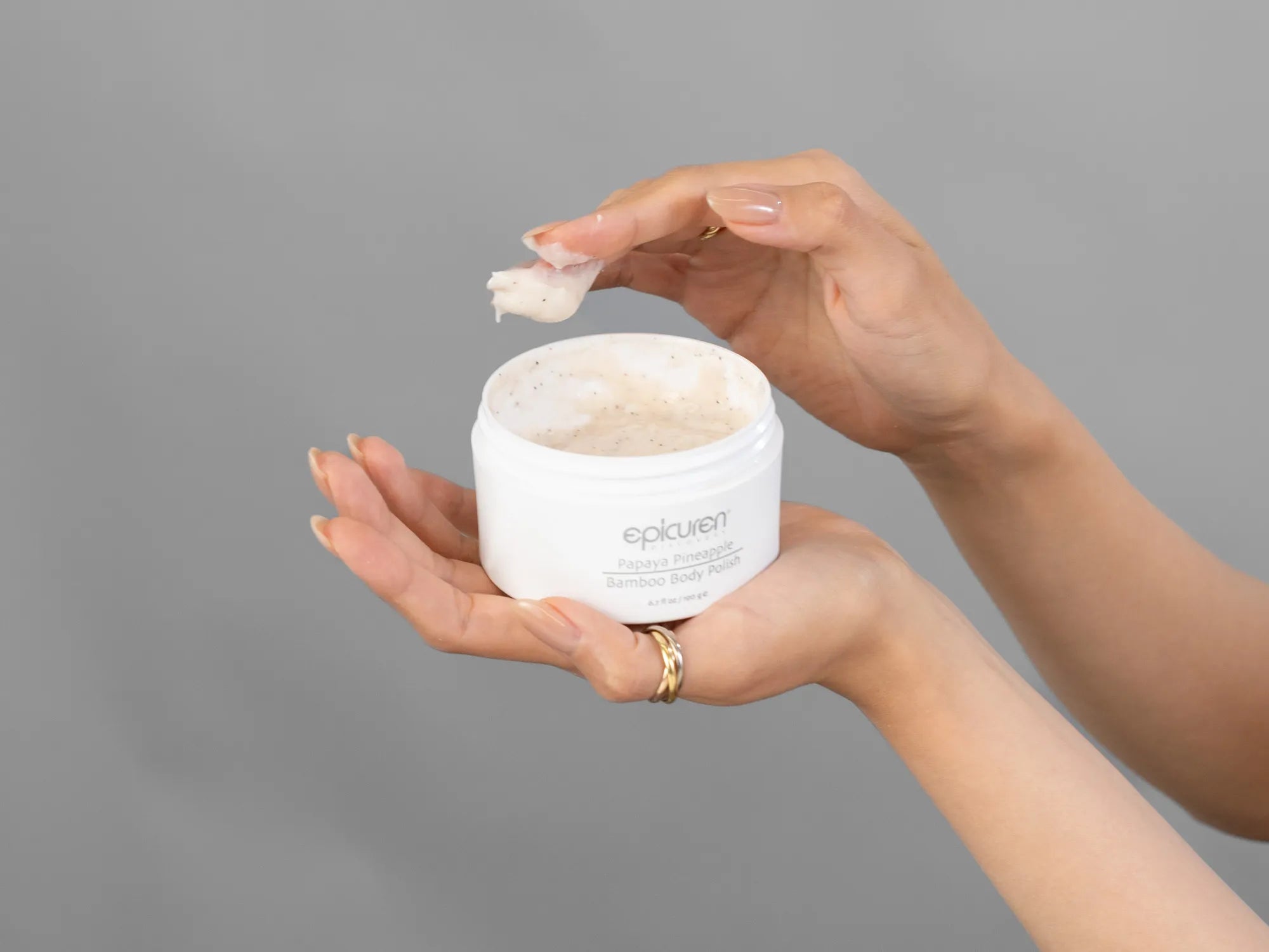 Closeup of Laziza from LAZ Skincare holding up a bottle of Epicuren Papaya Pineapple Bamboo Body Polish