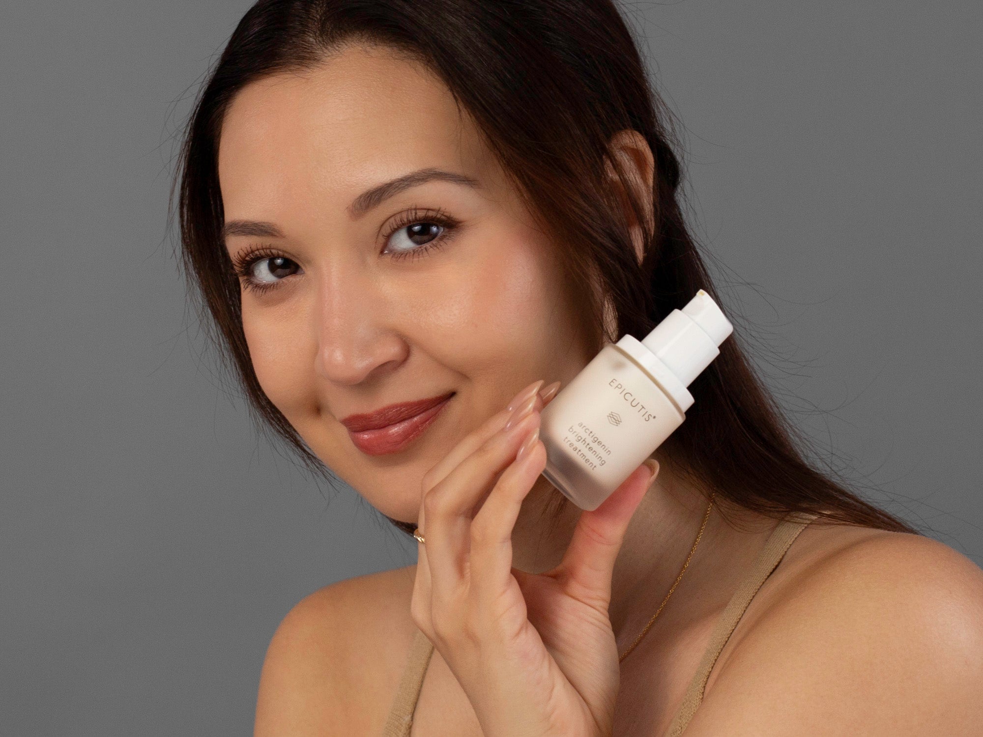 Laziza from LAZ Skincare holding a bottle of Epicutis Arctigenin Brightening Treatment up to her face