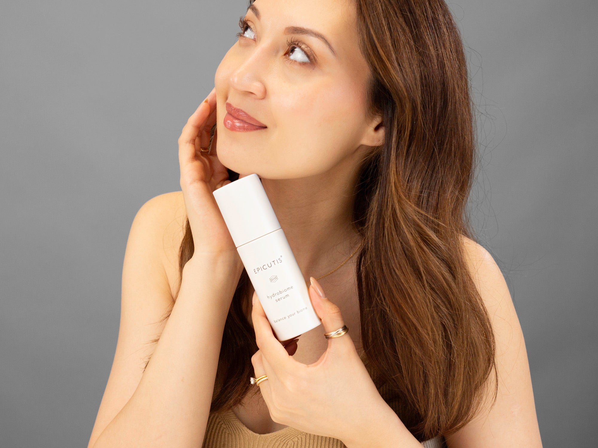 Laziza from LAZ Skincare holding a bottle of Epicutis Hydrobiome Serum up to her face