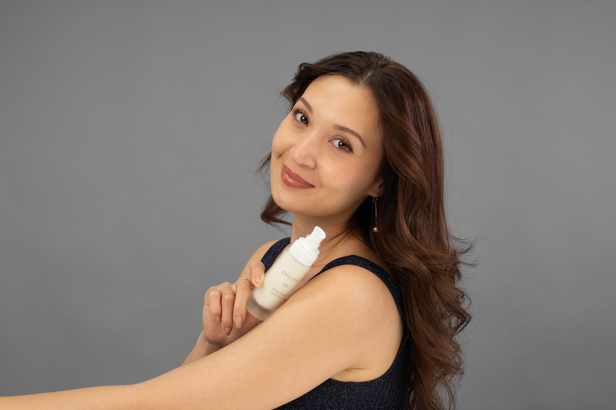 Laziza from LAZ Skincare holding a bottle of Epicutis Lipid Body Treatment in front of her