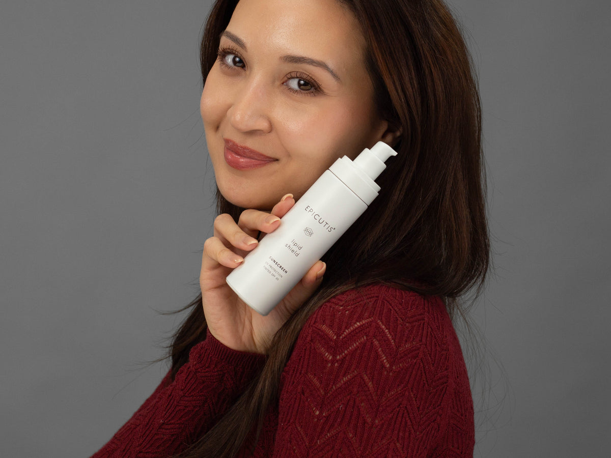 Laziza from LAZ Skincare holding a bottle of Epicutis Lipid Shield SPF 30 up to her face