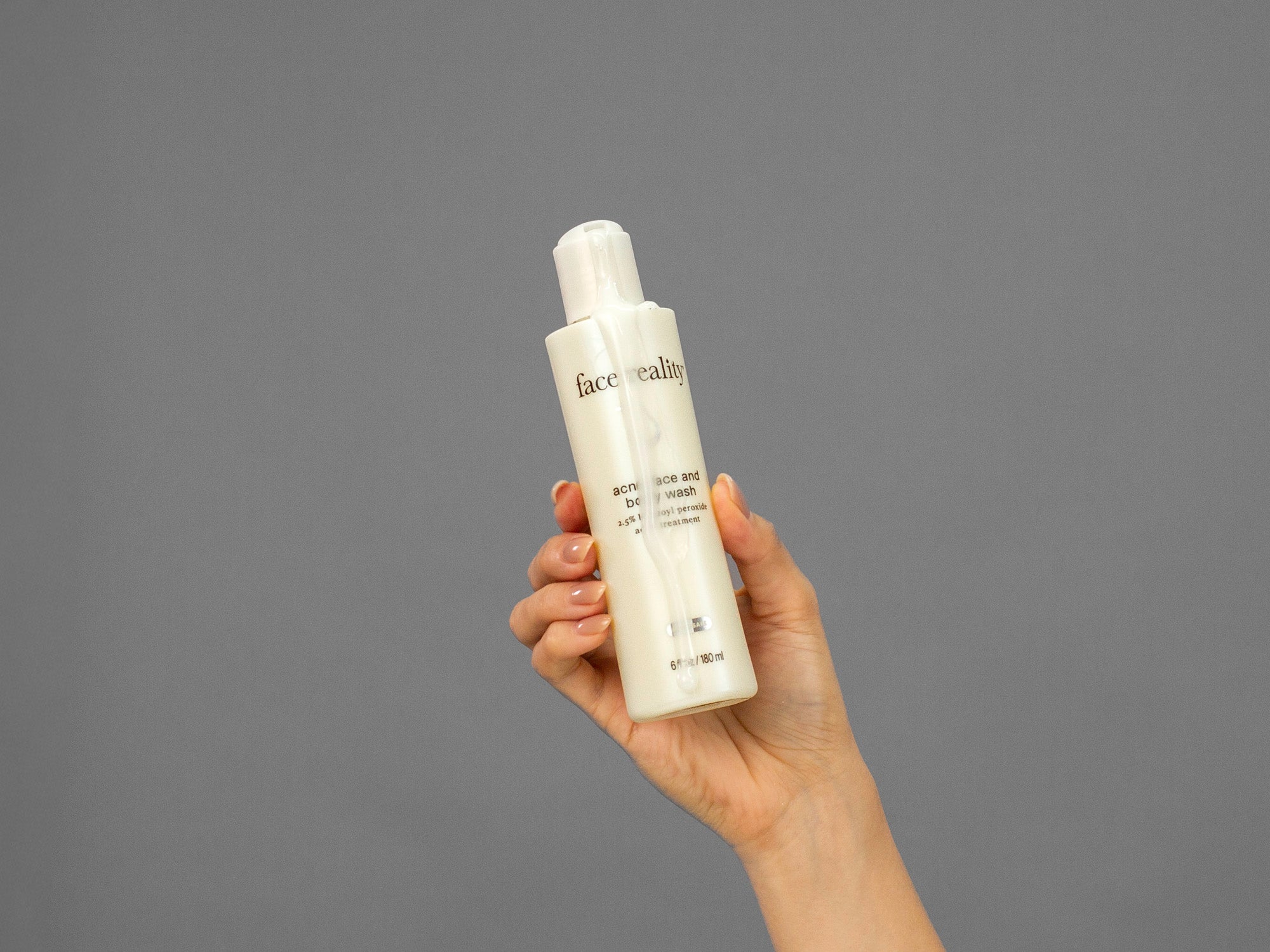 Closeup of Laziza from LAZ Skincare squeezing a bottle of Face Reality Acne Face & Body Wash