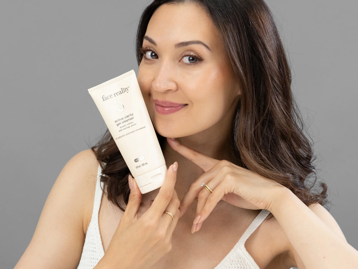 Laziza from LAZ Skincare holding a bottle of Face Reality Active Clarity Gel Cleanser up to her face