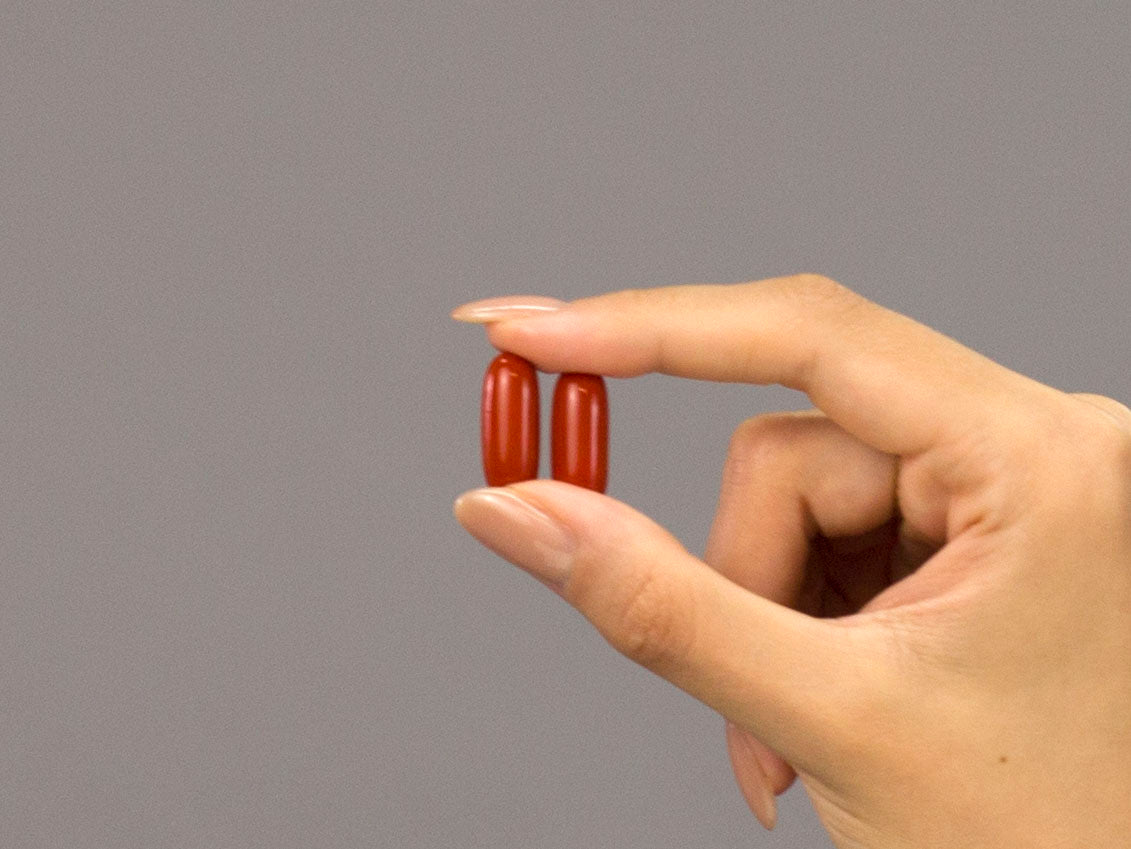 Closeup of Laziza from LAZ Skincare holding two capsules of Face Reality Clear Skin Balance supplements in her hand