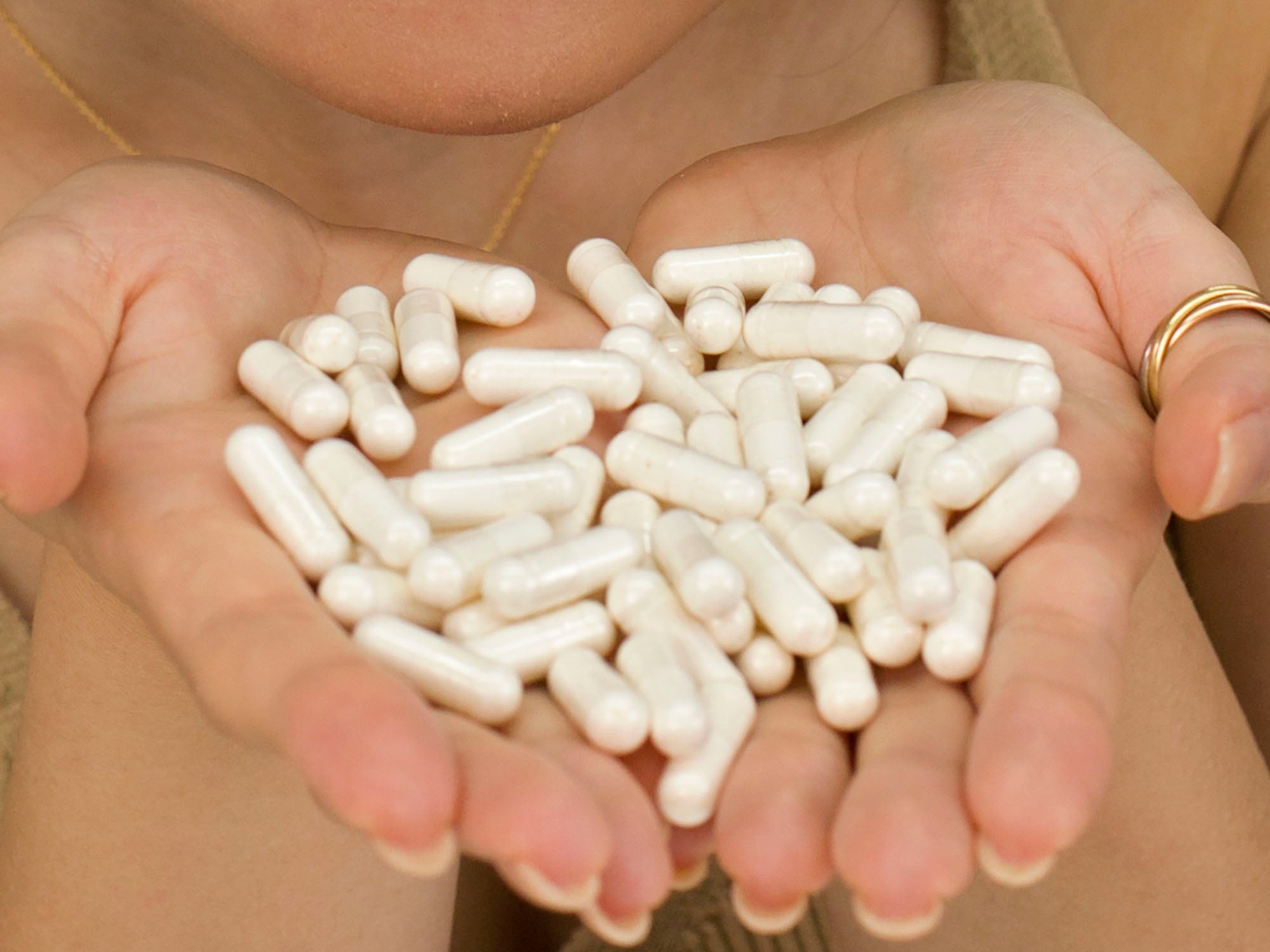 Closeup of Laziza from LAZ Skincare holding a bottle's worth of capsules of Face Reality Clear Skin Restore supplements in her hands