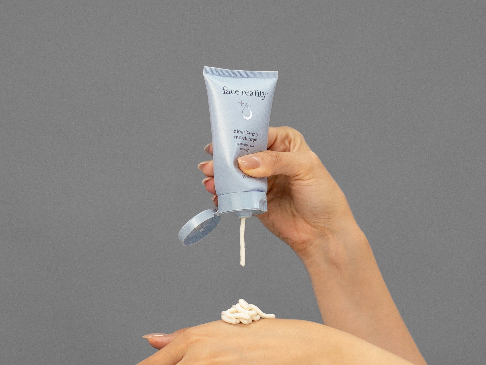 Closeup of Laziza from LAZ Skincare squeezing a bottle of Face Reality Clearderma Moisturizer onto her hand